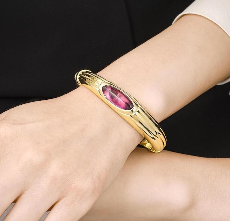 A lovely vintage bangle bracelet! The bangle contains an oval-cabochon amethyst, measuring approximately 22.45 x 8.65 mm, set in an 18K yellow gold bracelet with a hinged closure.

Stones: Amethyst

Metal: 18K Yellow Gold

Dimensions: 7