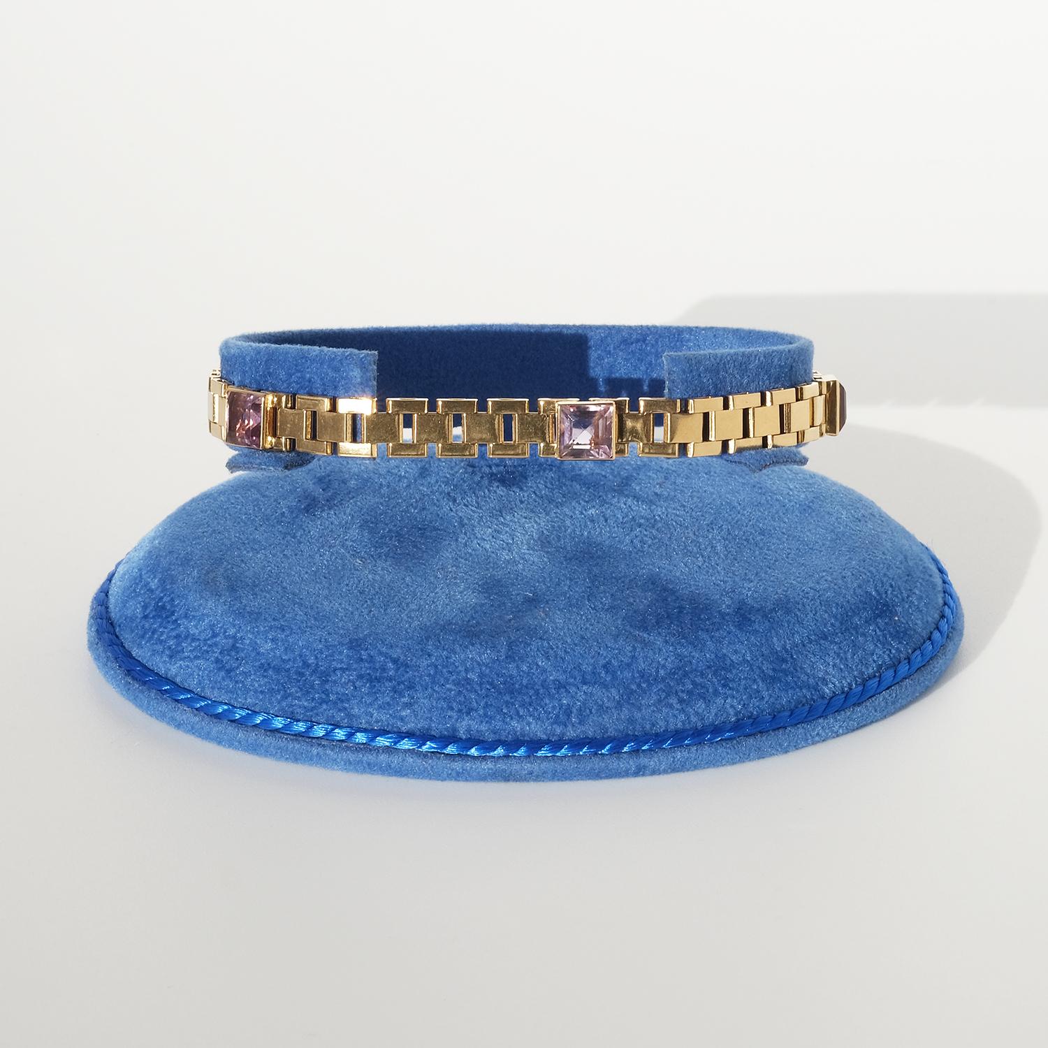This 18 karat gold bracelet features a series of sleek, rectangular brick links arranged in an offset pattern that creates a refined, structured design. Set into the bracelet are five square-cut amethysts, adding a touch of color and elegance to the