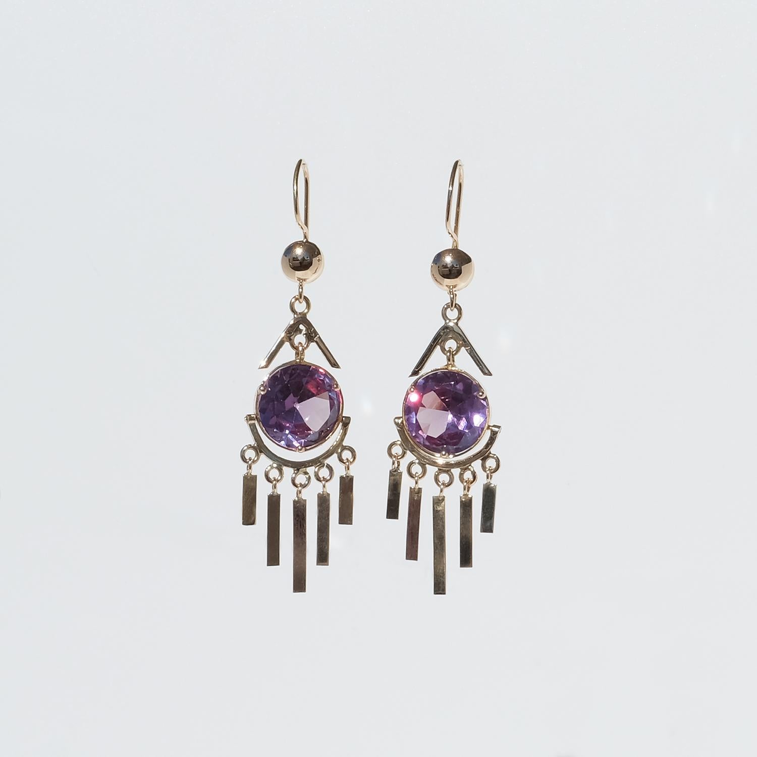 These 18 karat gold earrings are adorned with brilliant cut amethysts. Below each amethyst dangles five flat golden bars making the earrings look like luxurious dream catchers. They have so called fish hook backs which are secured in the back.

The