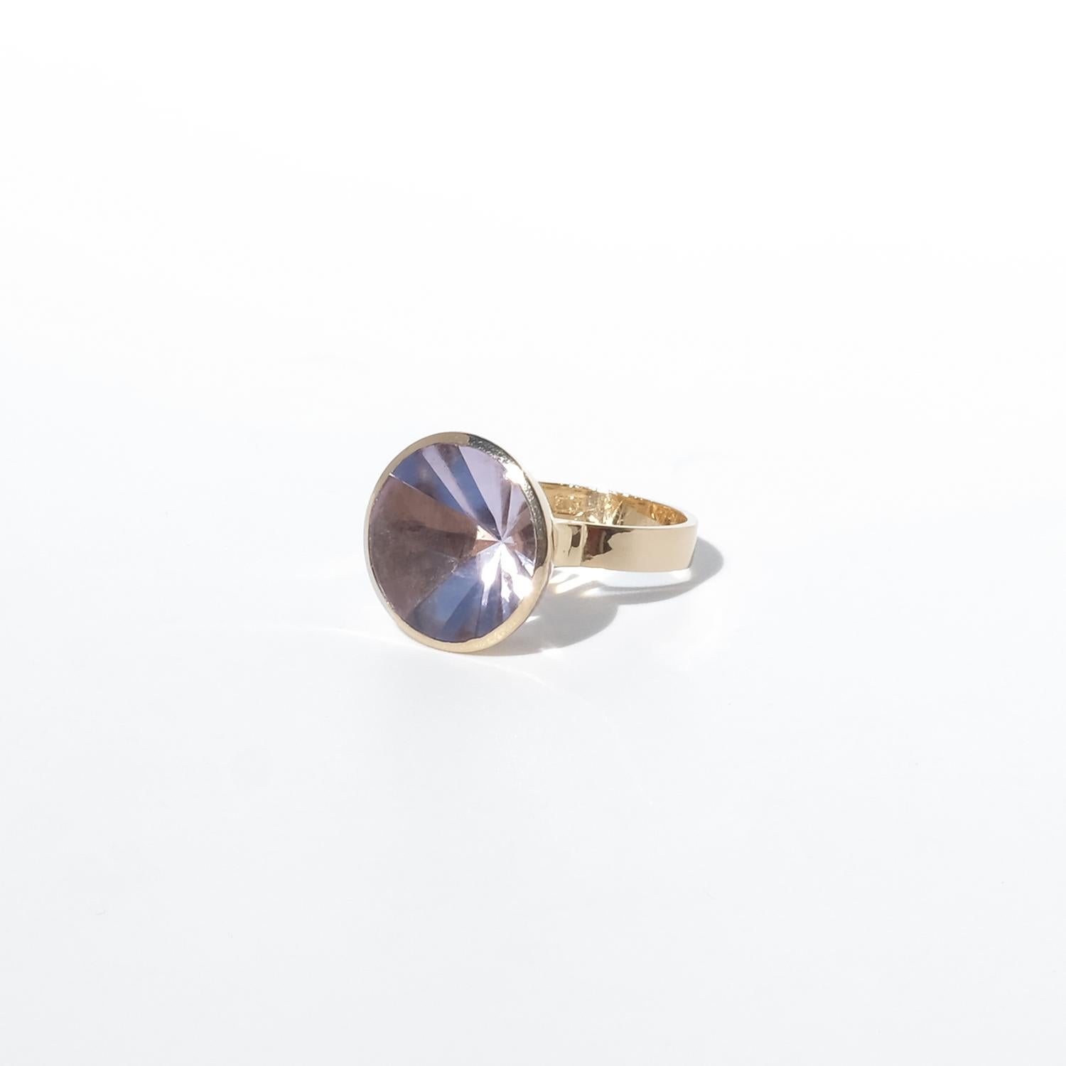 Questo anello è realizzato in oro a 18 carati e presenta al centro una splendida ametista sfaccettata. La pietra presenta una delicata tonalità lavanda chiaro ed è tagliata con precisione con un sorprendente motivo radiale che crea un dinamico gioco