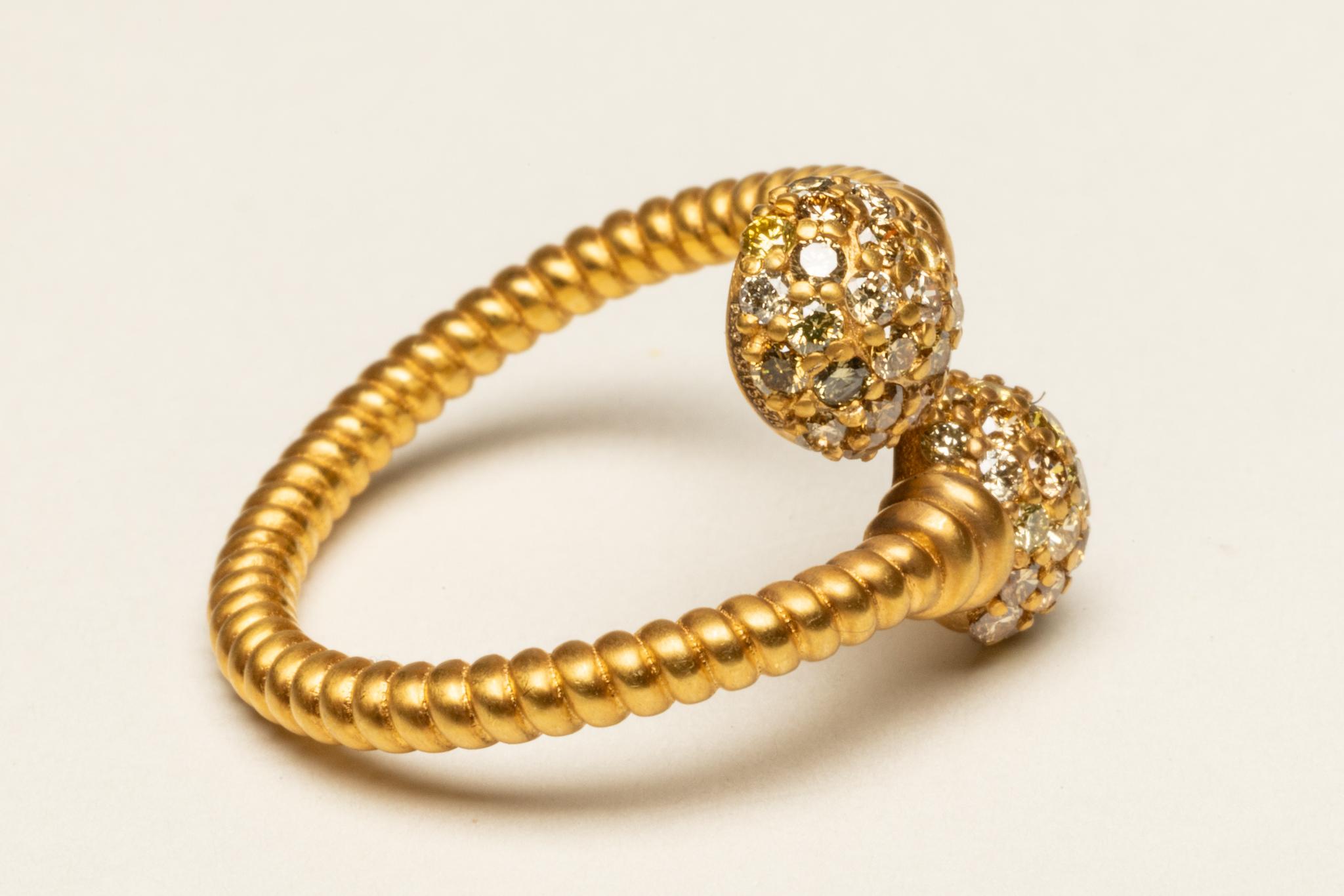 Un anello eccezionale composto da due fasce d'oro 18K incrociate e attorcigliate che terminano con sfere di diamanti champagne rotondi, taglio brillante e incastonati a pavé.  I diamanti hanno un totale di 0,70 carati.  Ha una certa regolabilità e