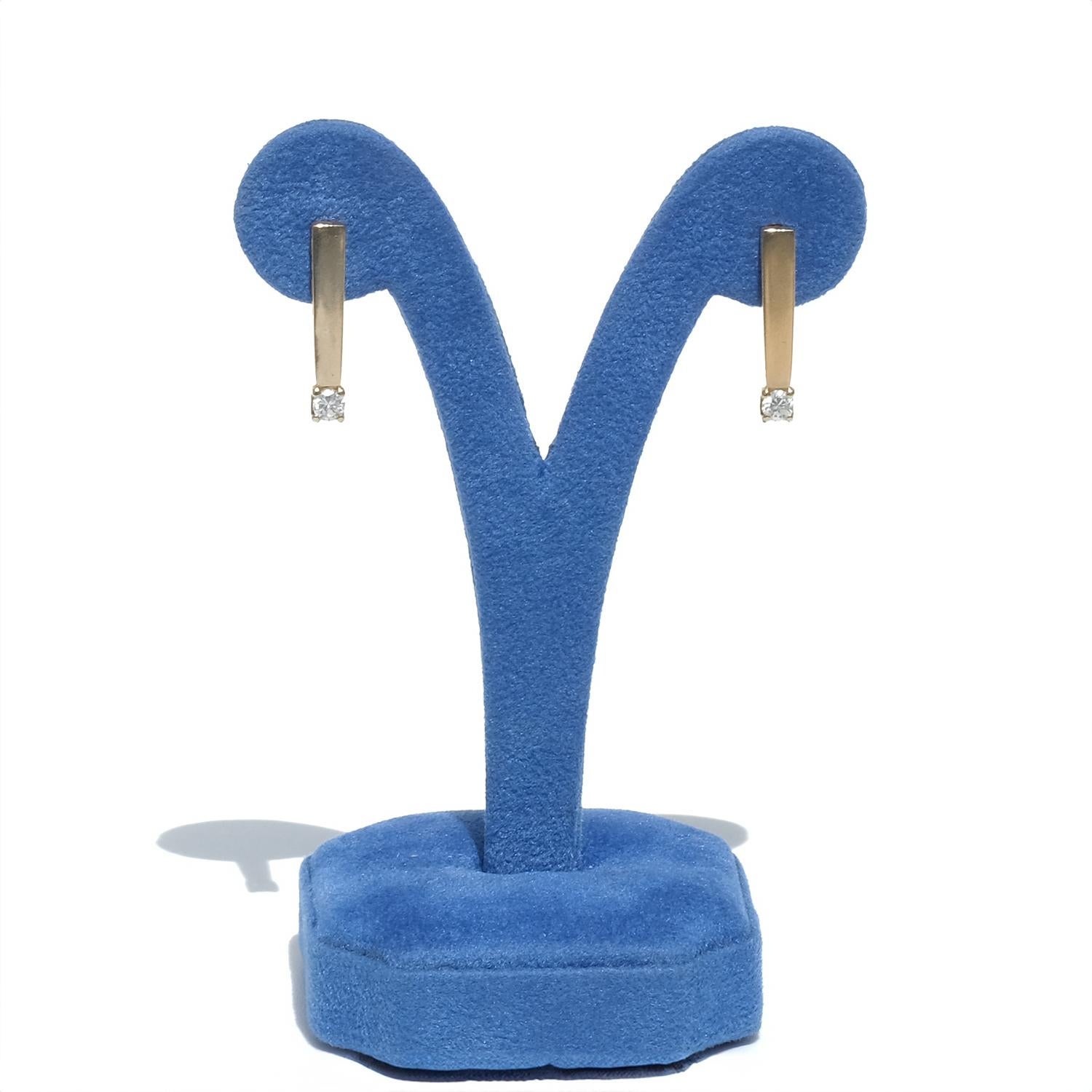 Questi orecchini in oro a 18 carati presentano un elegante design a barretta verticale che pende elegantemente dall'orecchio, ciascuno ornato da un brillante diamante rotondo per un totale di circa 0,38 carati per la coppia. La forma minimalista