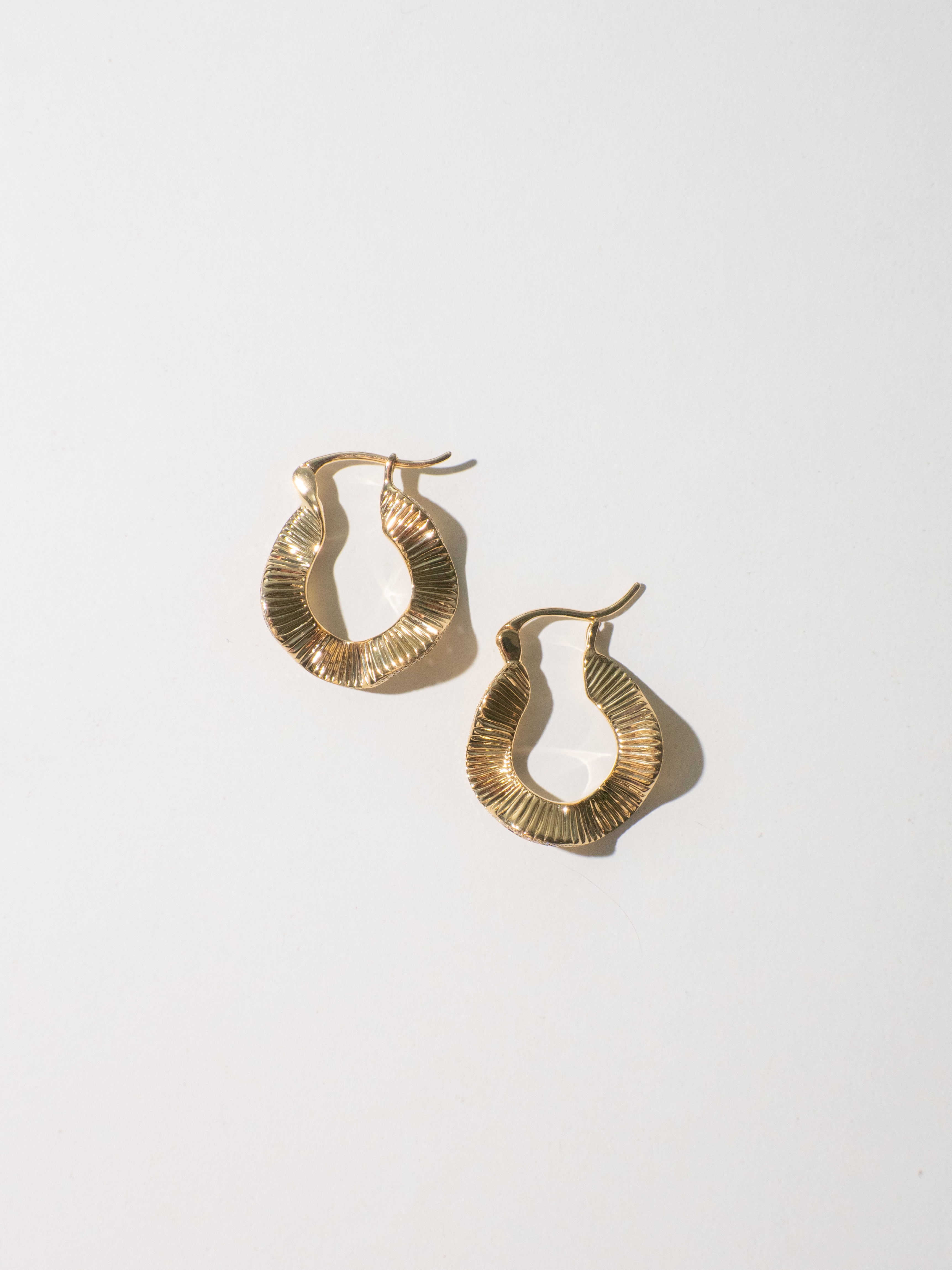 Estos elegantes pendientes de diseño ondulado están elaborados en oro macizo de 18 quilates y presentan una elegante curva acentuada con una hilera de brillantes diamantes naturales a lo largo del borde exterior. Su forma fluida y escultural evoca