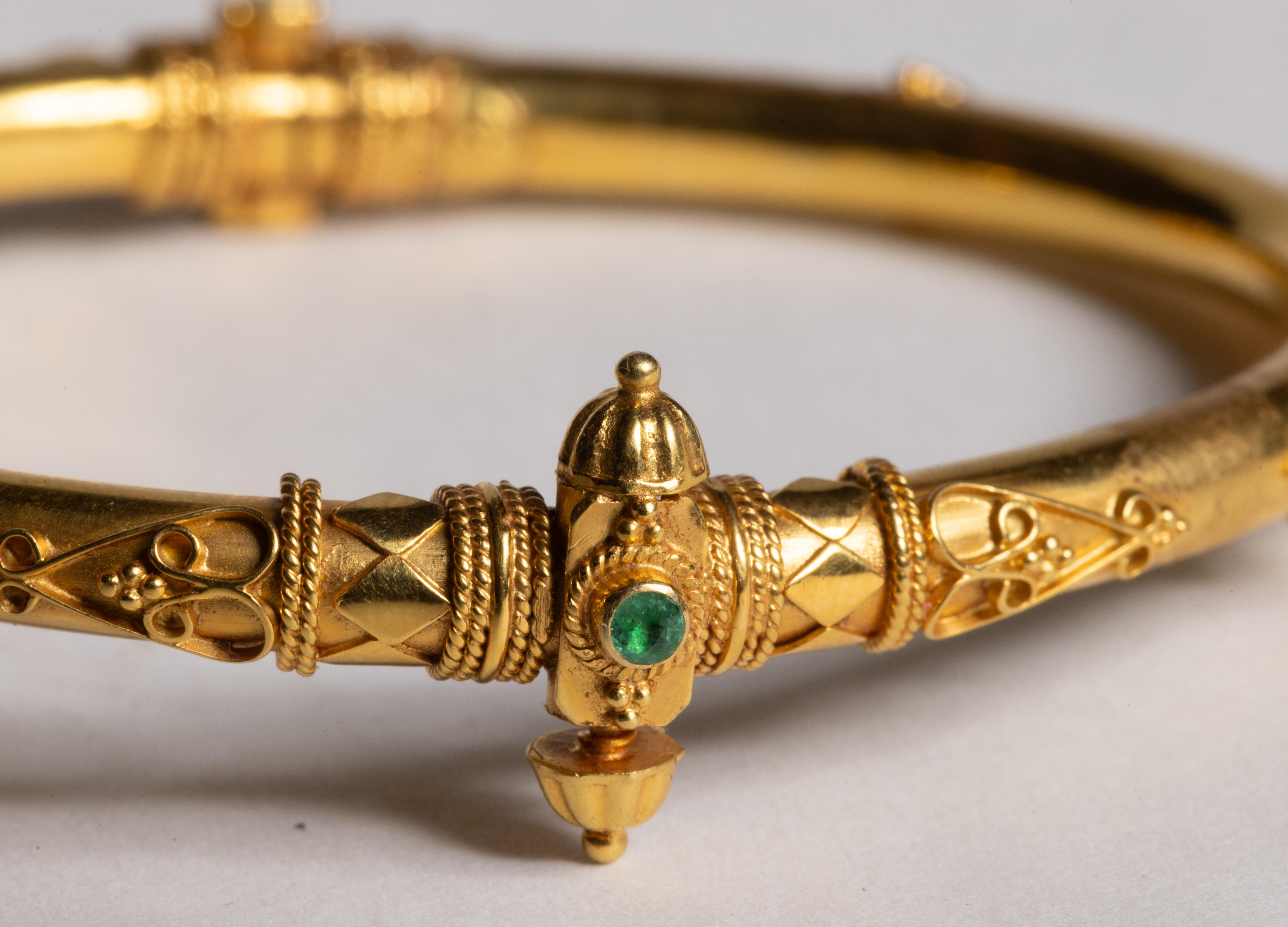 un raffinato braccialetto indiano in oro 18 carati con una raffinata lavorazione e granulazione e 7 smeraldi rotondi sfaccettati distribuiti lungo la parte superiore del braccialetto.  La chiusura si trova nella parte anteriore del bracciale e si