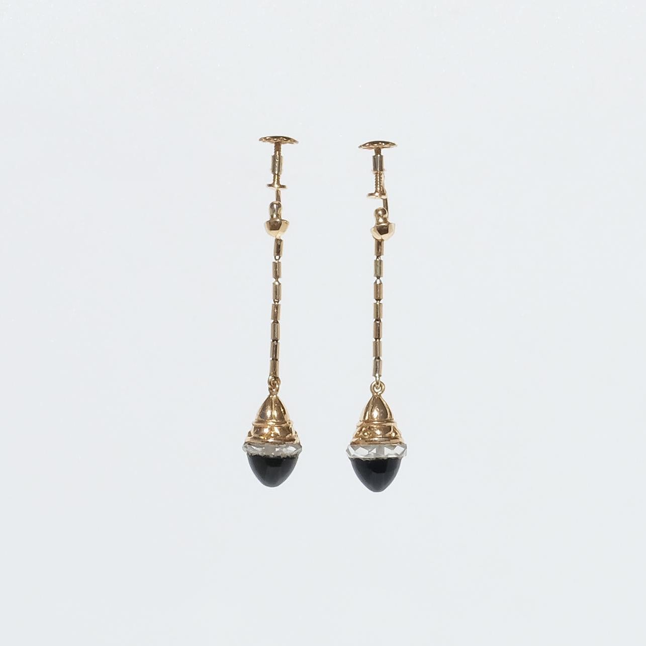 These 18 karat gold earrings are adorned with cabochon cut onyx-stones and a border of old-cut glass. The pendants dangle beautifully on a 20 mm long golden bamboo link chain. To keep the earrings in place they have, as many of the earrings had