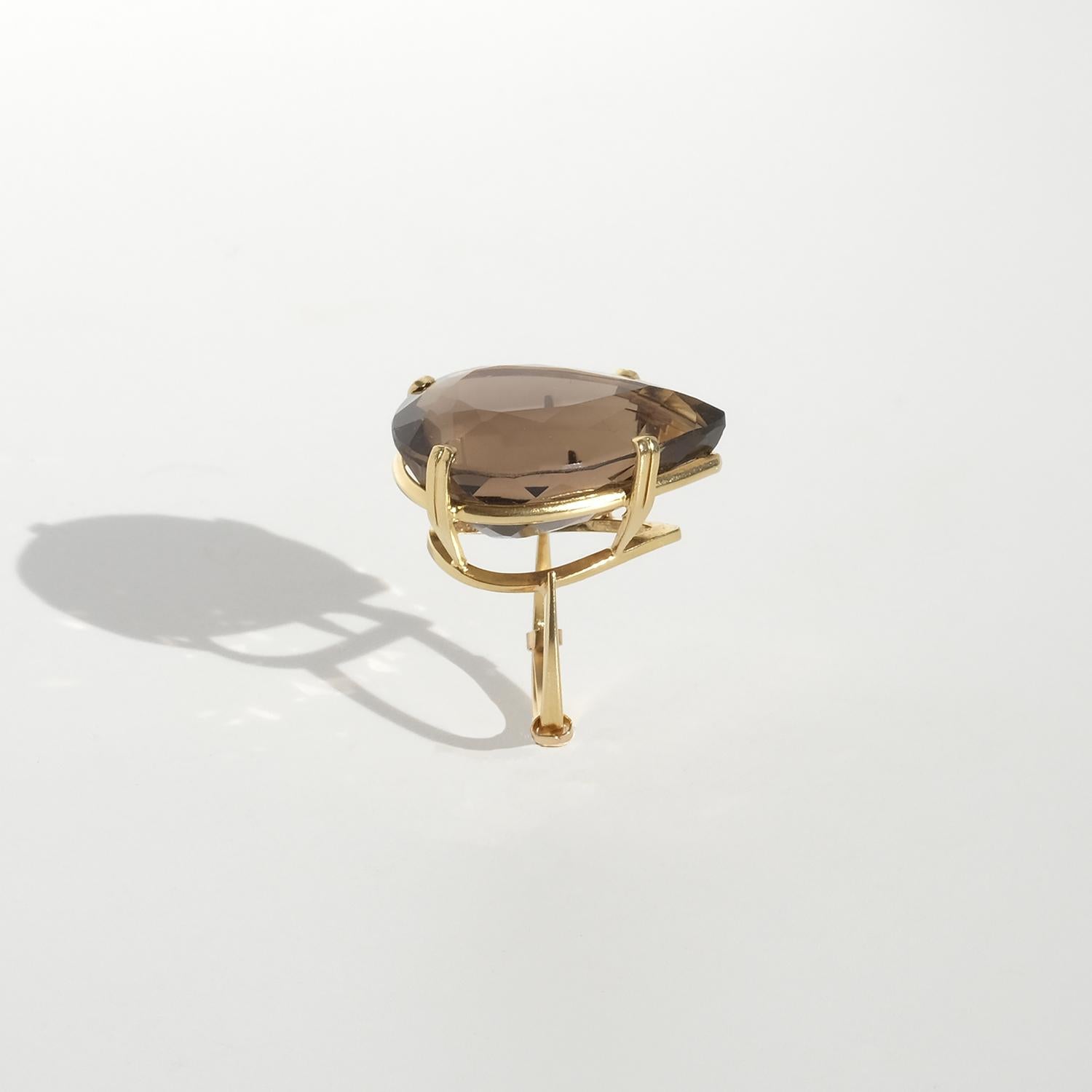 Questo anello vintage è realizzato in oro a 18 carati e incastonato con un grande quarzo fumé sfaccettato a forma di goccia. La pietra presenta una profonda tonalità marrone traslucida con riflessi nitidi. È custodito in una cornice scultorea aperta
