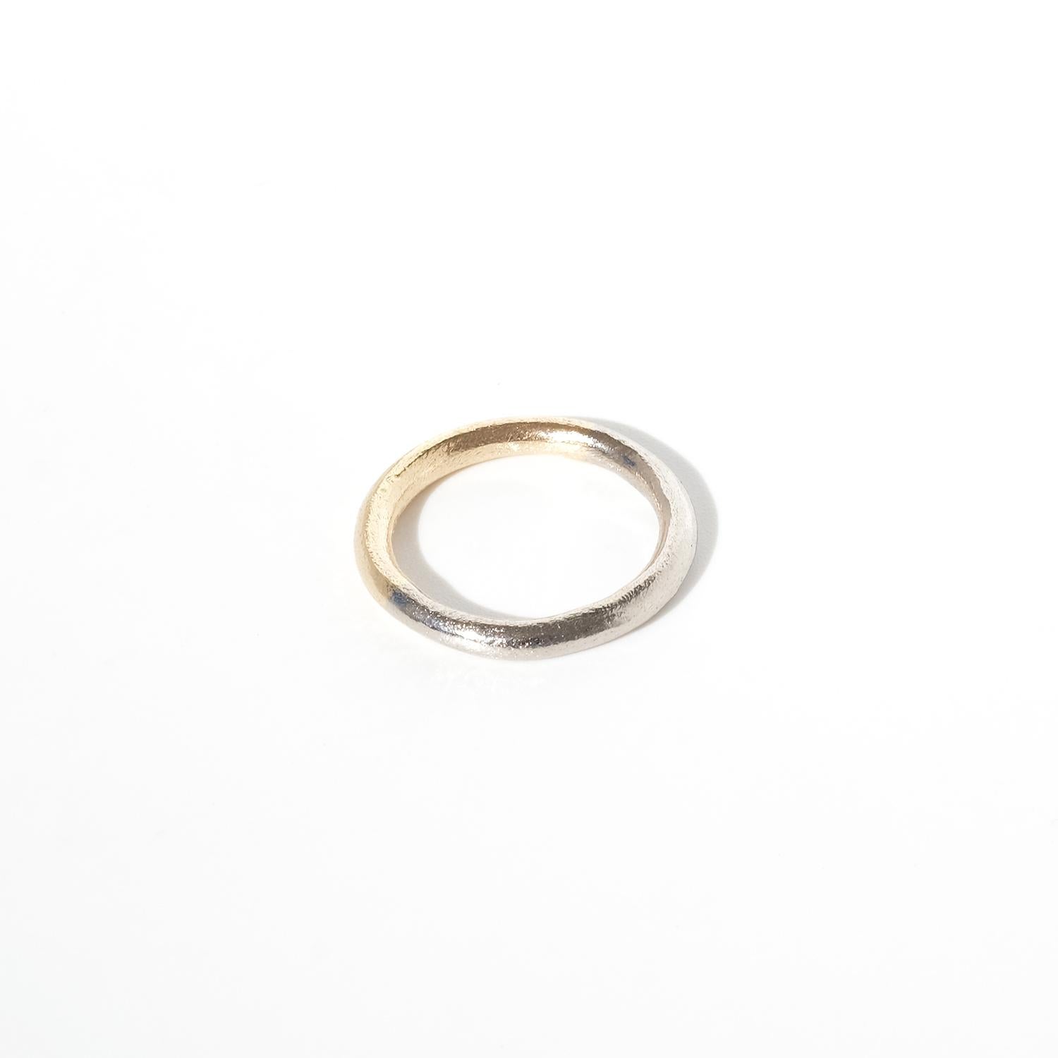 This ring is crafted in a combination of gold and white gold, with a subtle yet distinct color shift along the band, seamlessly blending the two metals. The band features a softly rounded, organic form with a slightly irregular, textured surface