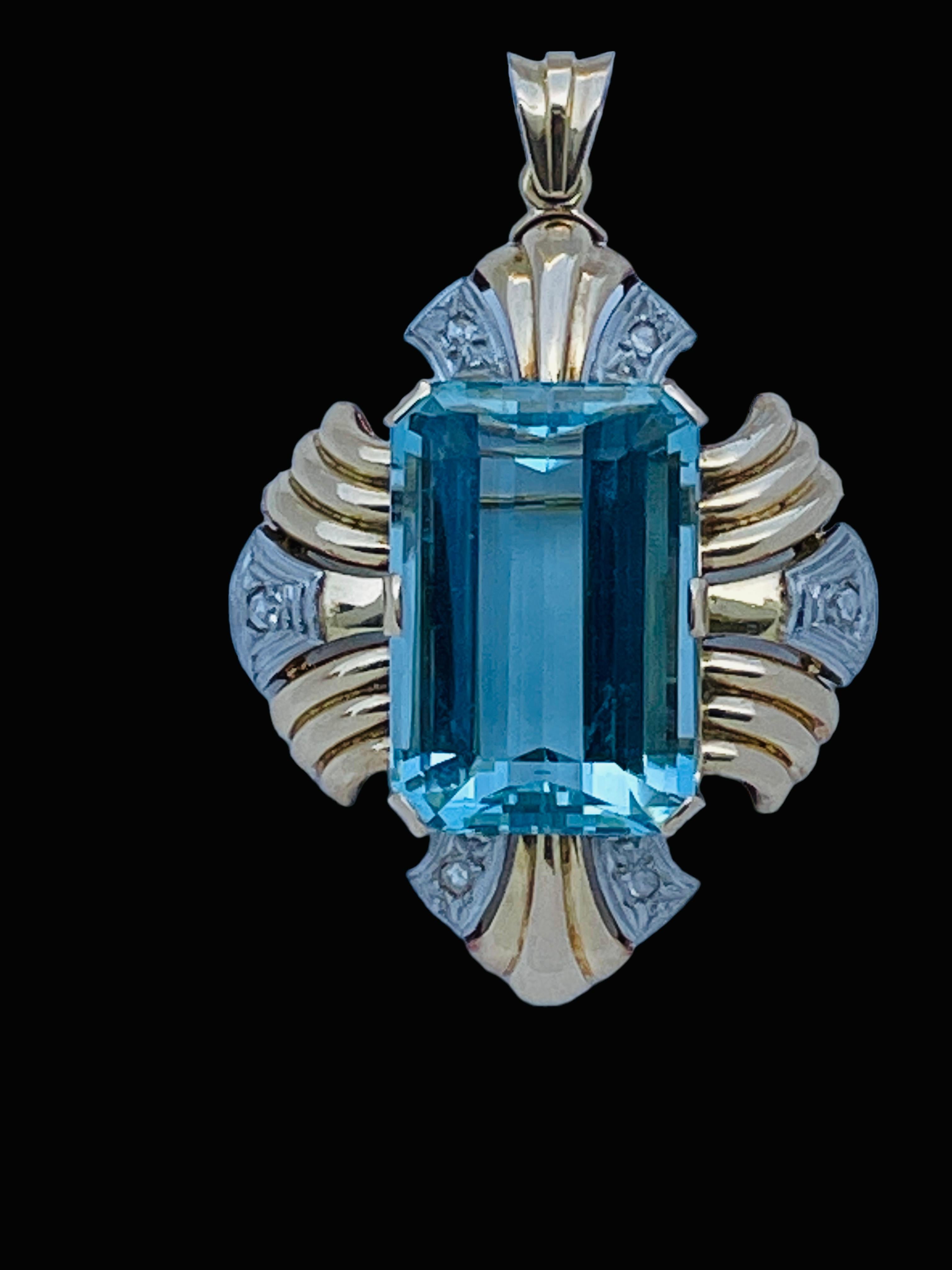 This is an 18K yellow and white gold aquamarine and diamonds pendant/brooch. It depicts an emerald cut aquamarine of 22.18ct in prong setting in the center. It is adorned with yellow gold Fleur de Lis edge like in addition to two set of triplets