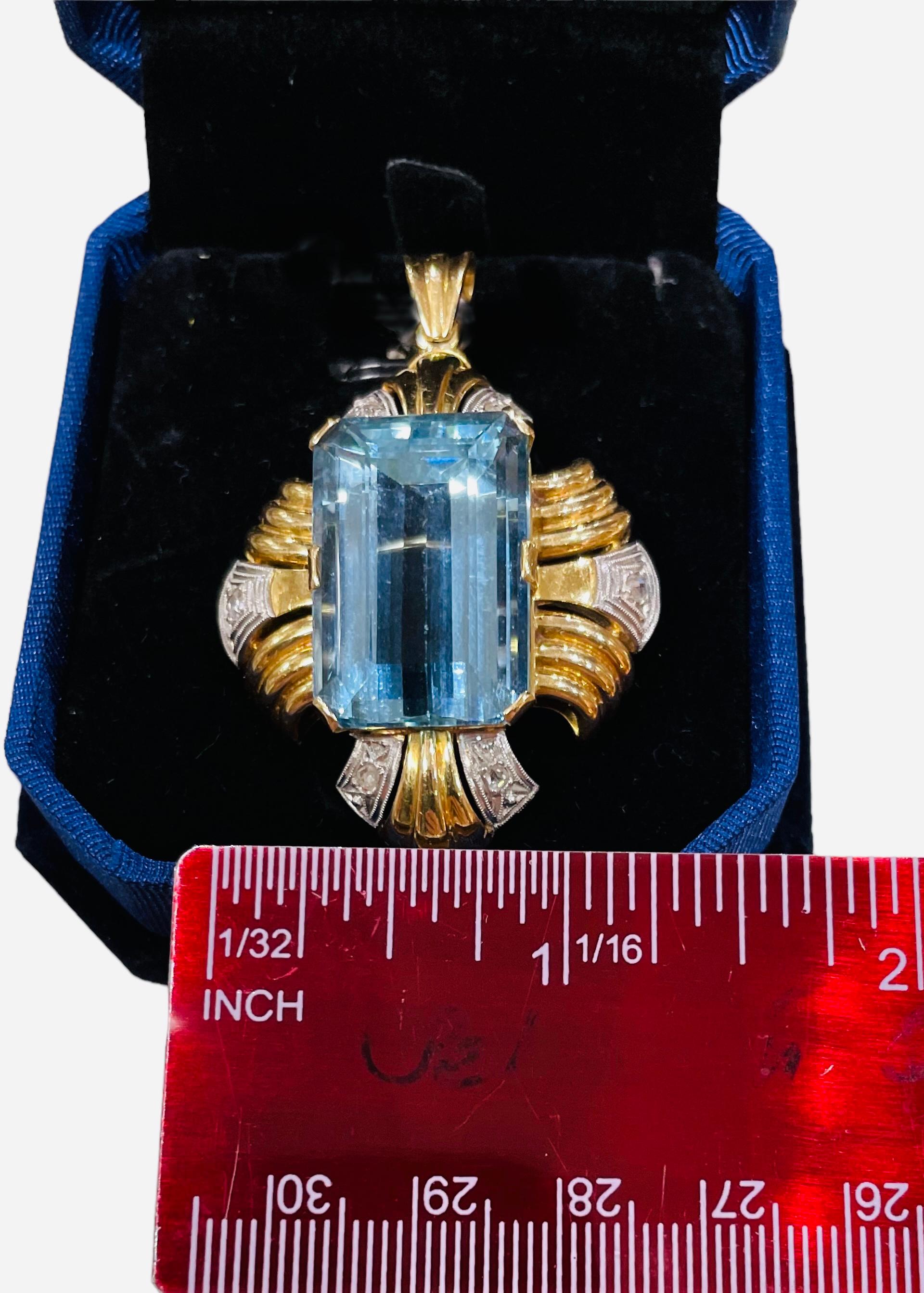 This is an 18K yellow and white gold aquamarine and diamonds pendant/brooch. It depicts an emerald cut aquamarine of 22.18ct in prong setting in the center. It is adorned with yellow gold Fleur de Lis edge like in addition to two set of triplets
