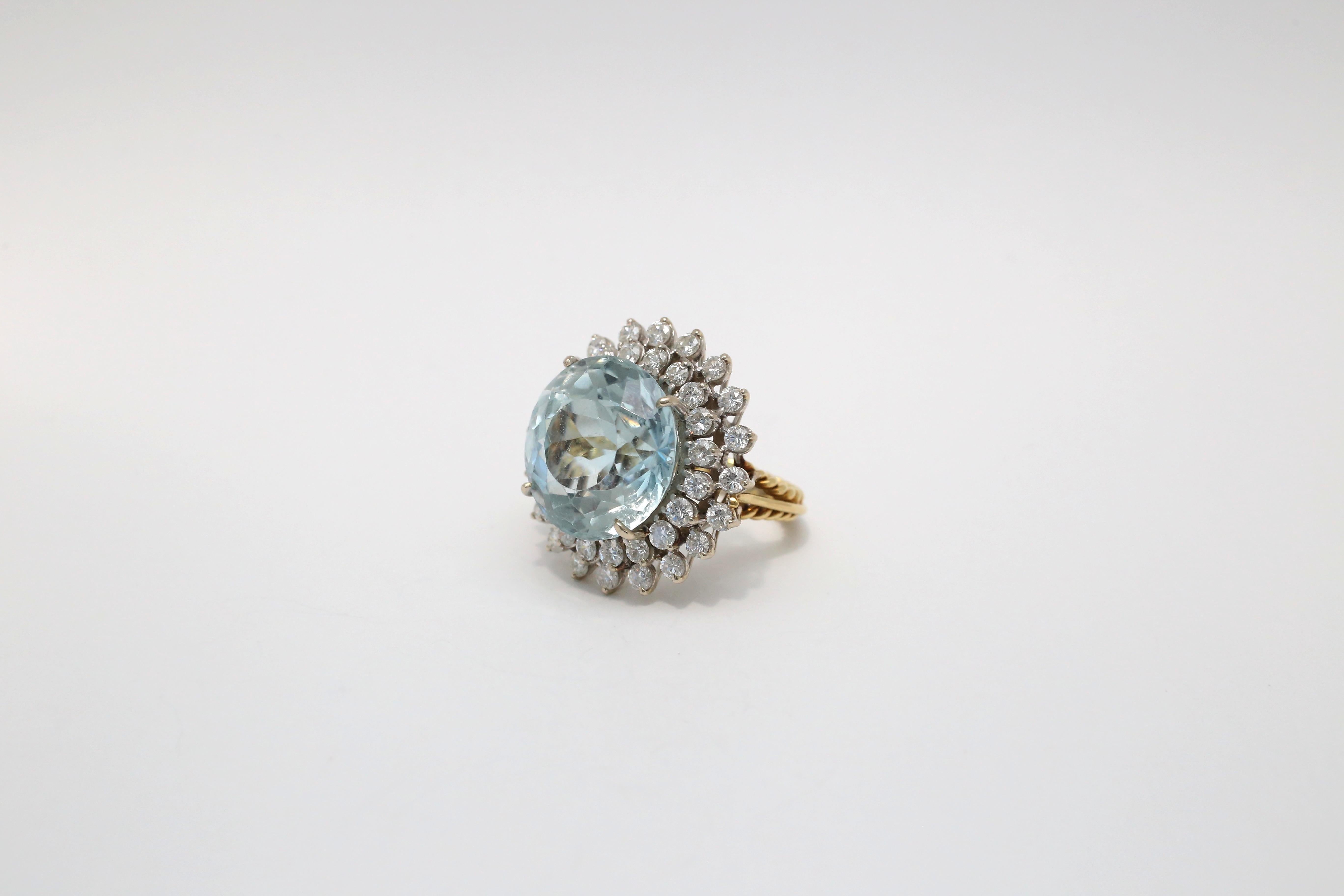 This stunning 18k gold ring showcases an exquisite design centered around a magnificent approximately 26-carat aquamarine gemstone. The large, round-cut aquamarine sparkles with a delicate icy-blue hue, creating a captivating focal point.