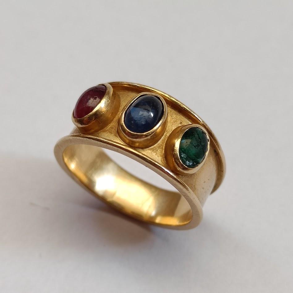 An 18k yellow gold band ring with an oval cabochon-cut sapphire, emerald, and ruby. Probably mid-20th century. French eagle's head hallmark and another unidentified one.
Good condition, normal wear.

Size EU 55 - US 7 1/4 - UK O (approx.)
Weight