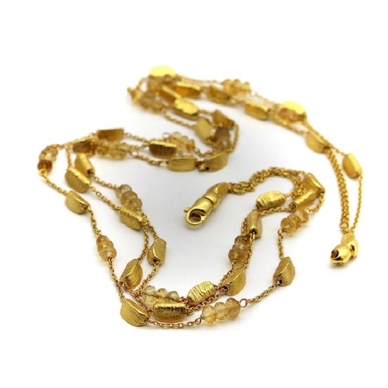 This 18k gold necklace consists of three strands of alternating gold bars and citrine briolette beads suspended between delicate gold chain. The shapes in this necklace are reminiscent of gold nuggets: the bars are moon-shaped wedges with a textured