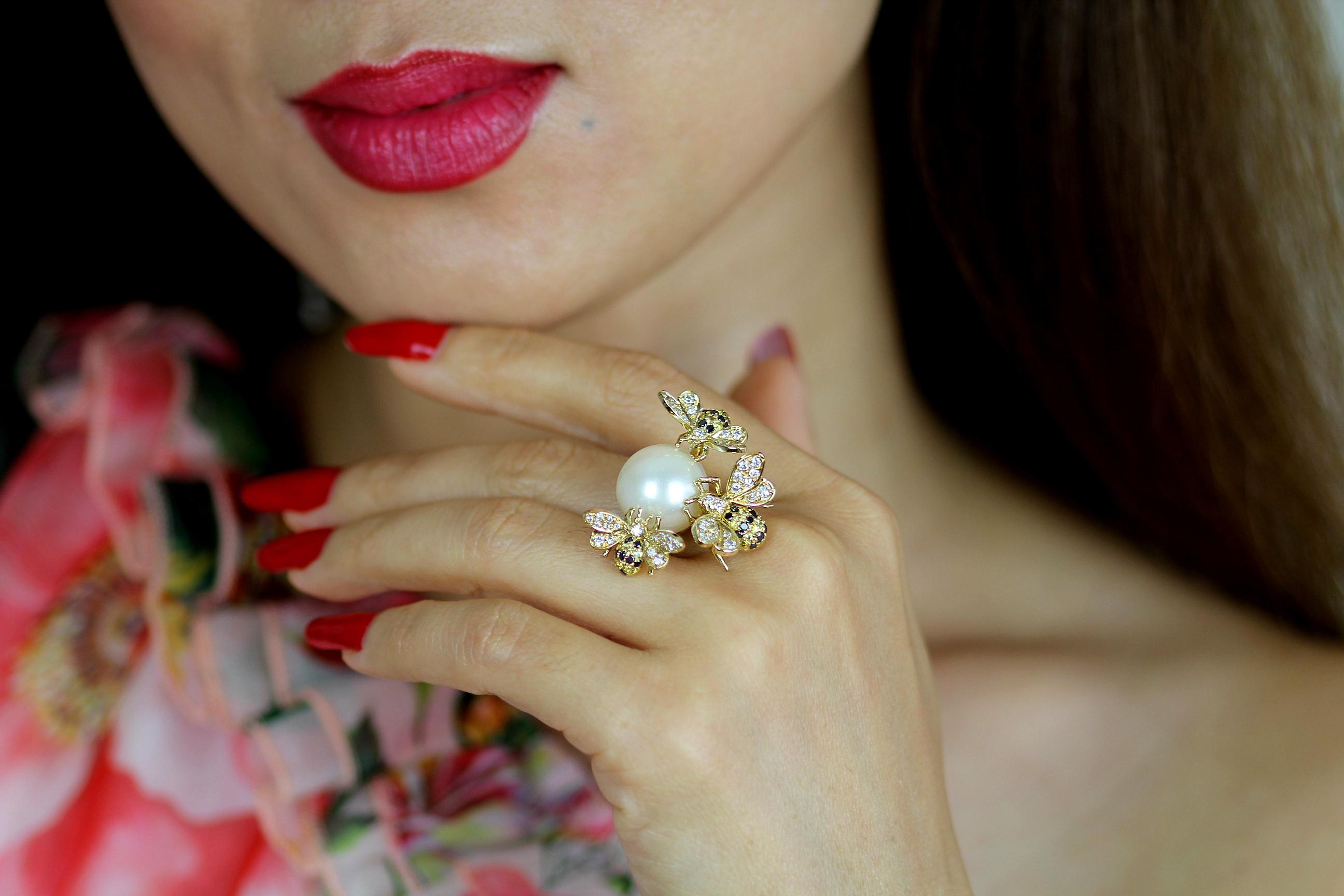 Une bague de cocktail fascinante et magnifiquement réalisée en or jaune 18 carats, ornée d'une impressionnante perle de culture en son centre. L'imposante perle d'un blanc glacé (14,5 × 13,0 mm) est entourée de trois abeilles aux détails exquis,