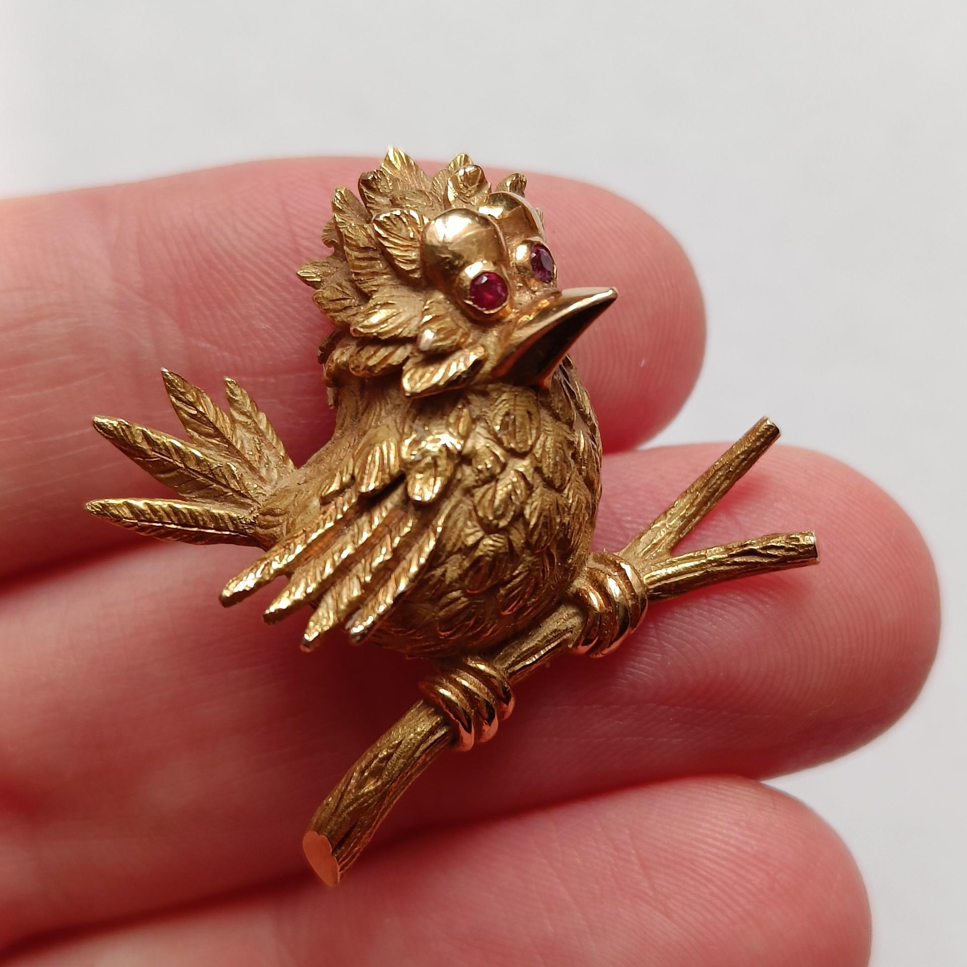 An 18 carat gold brooch depicting a bird perched on a branch. Two faceted red rubies as eyes. High-quality work from the Adolphe Chretien atelier, France. Estimated to be from the 1950s or 1960s. Various hallmarks. 

Excellent