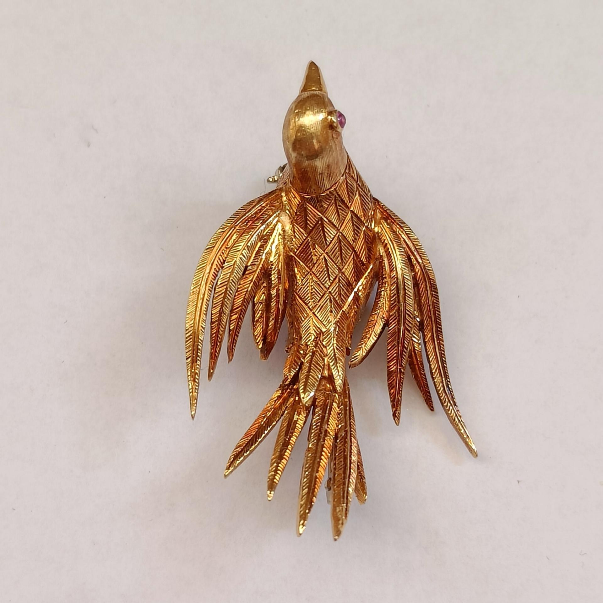 An 18 carat yellow gold brooch depicting a bird. Beautiful chiseled decorations all over the body. Pink gemstone as the eye. Stamped 750 and unidentified maker mark. Pin in white gold (stamped). Good condition.

Dimensions: 4x2.5 cm (approx)
Weight: