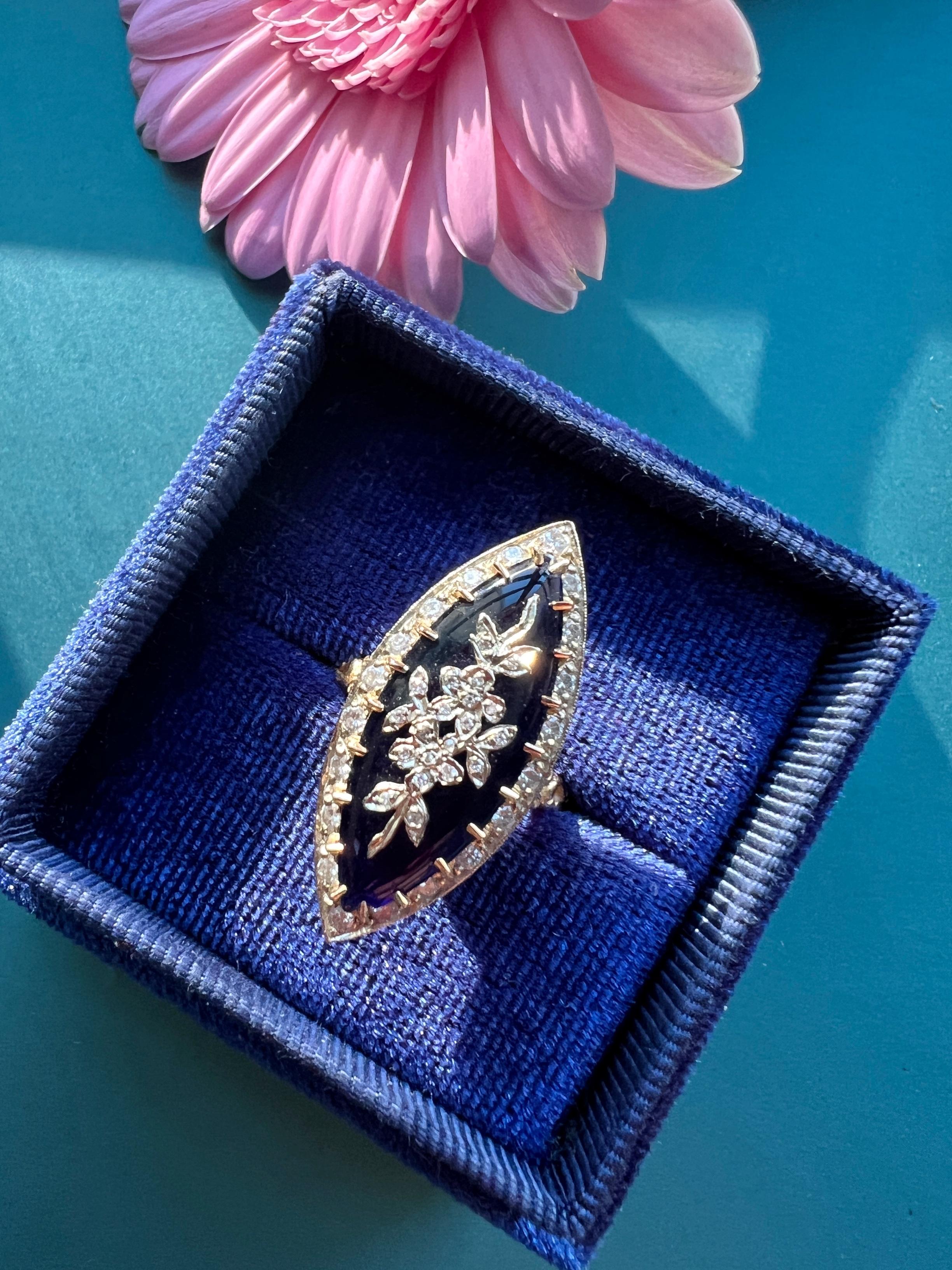 For sale a beautiful and important 18K gold marquise ring, featuring sparkling diamond flowers on a royal blue color glass cabochon panel. The central panel is prong set and is surrounded by 20 dazzling old cut diamonds. The head of the ring