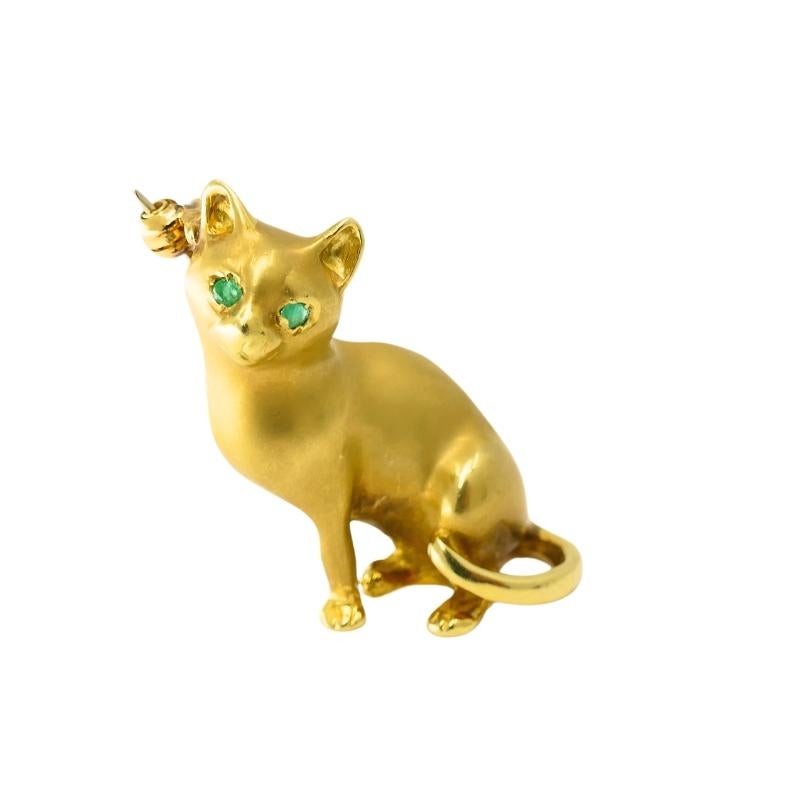 This cat brooch has a charming, lifelike quality. The matte gold finish gives the cat a soft appearance, as if it's been captured mid-pose. Its slender body and gracefully curved tail add to its elegant shape. The cat's eyes are set with bright