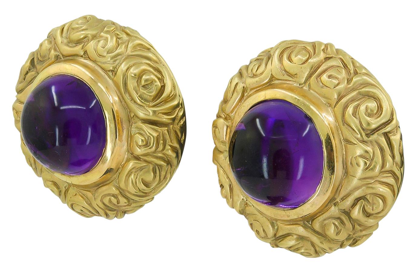 Ein Paar Ohrringe aus 18 Karat Gelbgold, besetzt mit einem Amethyst-Cabochon.
Jeder Amethyst-Cabochon ist ca. 12 mm groß. Jeder Ohrring misst ca. 1″ im Durchmesser und 0,60″ in der Höhe. Ohrclips sind derzeit für nicht gepiercte Ohren gedacht, für