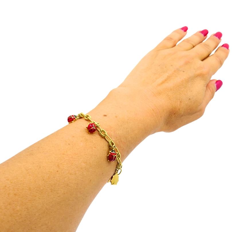 À la fois ludique et luxueux, ce bracelet vintage est orné d'un anneau de 18 carats.  Chaîne à double maillon en or, ornée de huit charms coccinelle en émail rouge 14k. Chaque charme est finement détaillé avec des accents d'émail rouge et noir