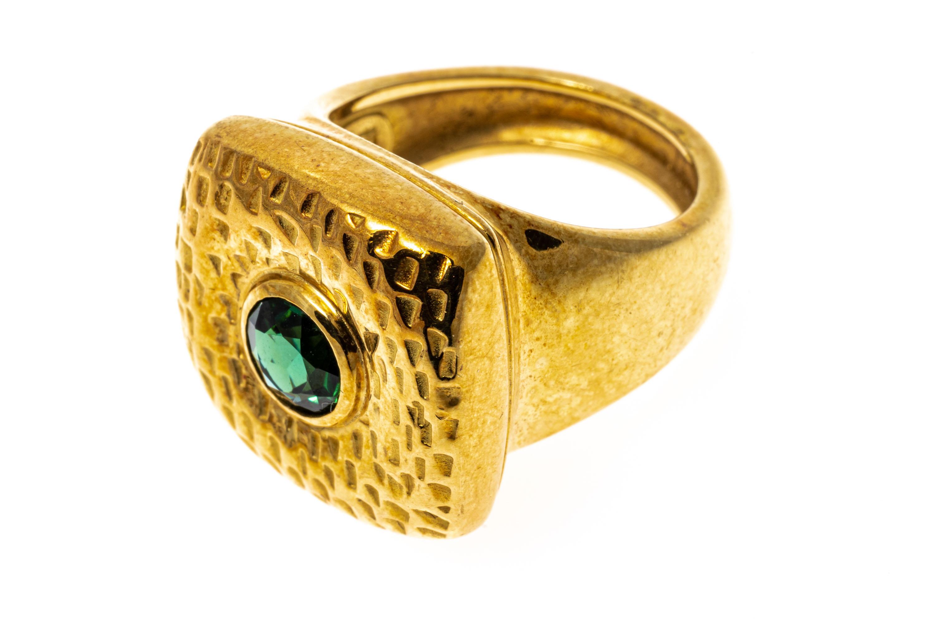 18k yellow gold ring. This beautiful, ultra contemporary ring has a wide, square cushion profile, with a mod, chased pattern adorned across the top and set with a round faceted, dark green color tourmaline, approximately 0.57 CTS, and bezel set. The