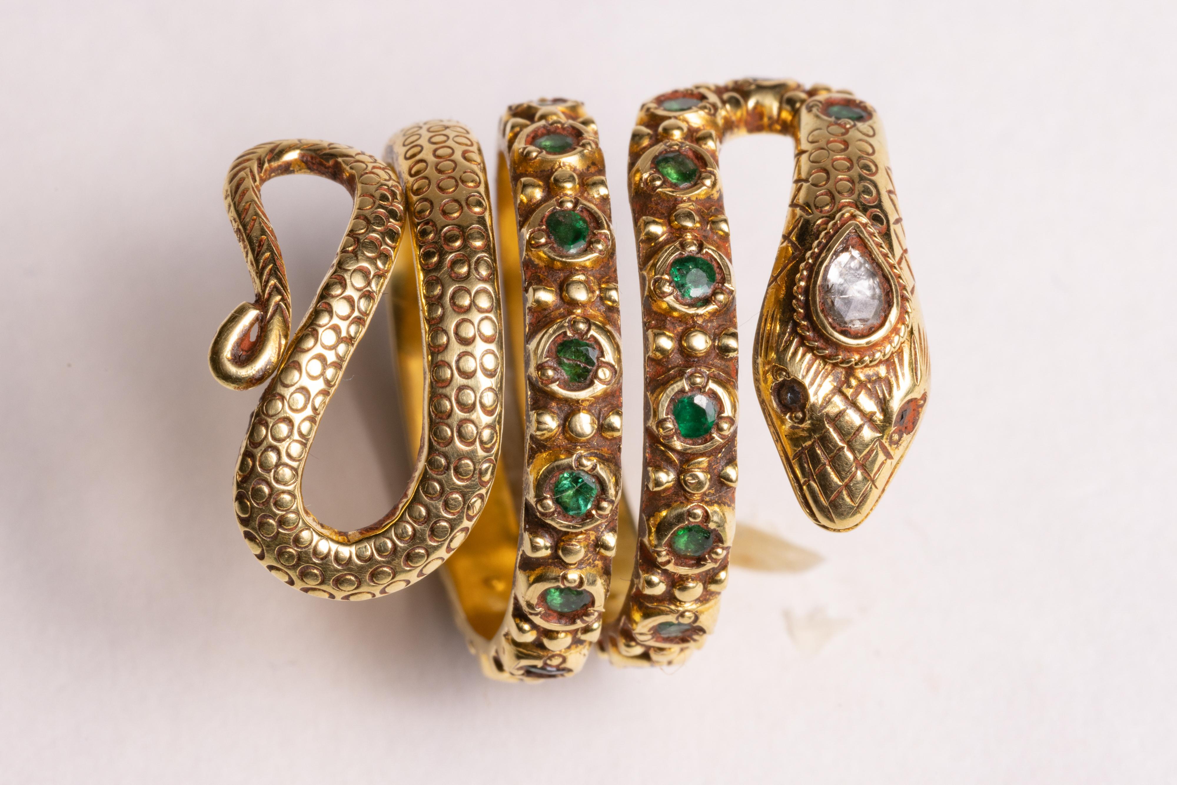 An amazing 18K gold coiled snake ring with rounded, faceted emeralds around the band and hand-tooled gold workmanship eliciting the scales of the snake.  The third eye is a faceted, pear-shaped diamond and has small round faceted rubies for the