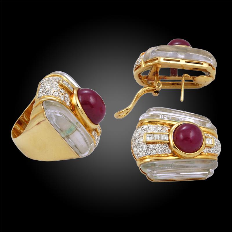 Comprising a cocktail ring centering upon a bezel-set cabochon ruby to the pavé-set diamond surround and flanked by fluted rock crystal, a pair of ear clips en suite, mounted in gold. 
ring size 7
earrings 3.0 cm 