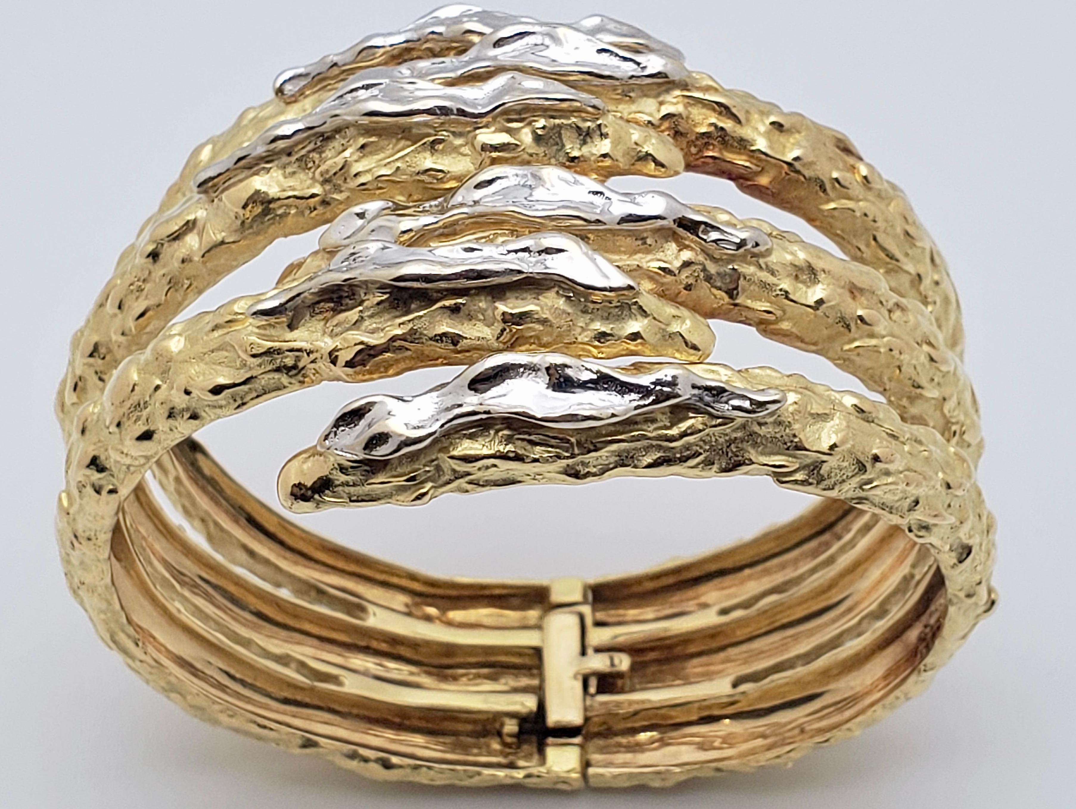 An extraordinary 18K yellow and white gold cuff claw snake bracelet. Circa 1960's, it features a one of a kind hammer gold finish, with the strokes of white gold on the front of the claws creating a vibrant contrast. This beautiful bracelet has been