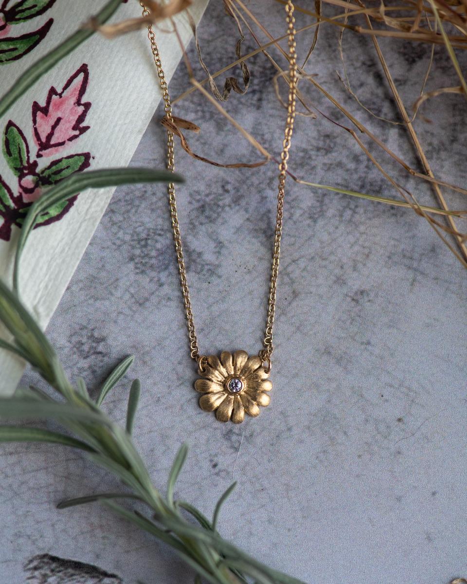 Introducing our exquisite hand-carved Diamond Daisy Necklace—a testament to timeless craftsmanship and natural elegance. Each petal of this remarkable daisy has been individually sculpted by Jennifer Rutheny, creating subtle dimension and texture