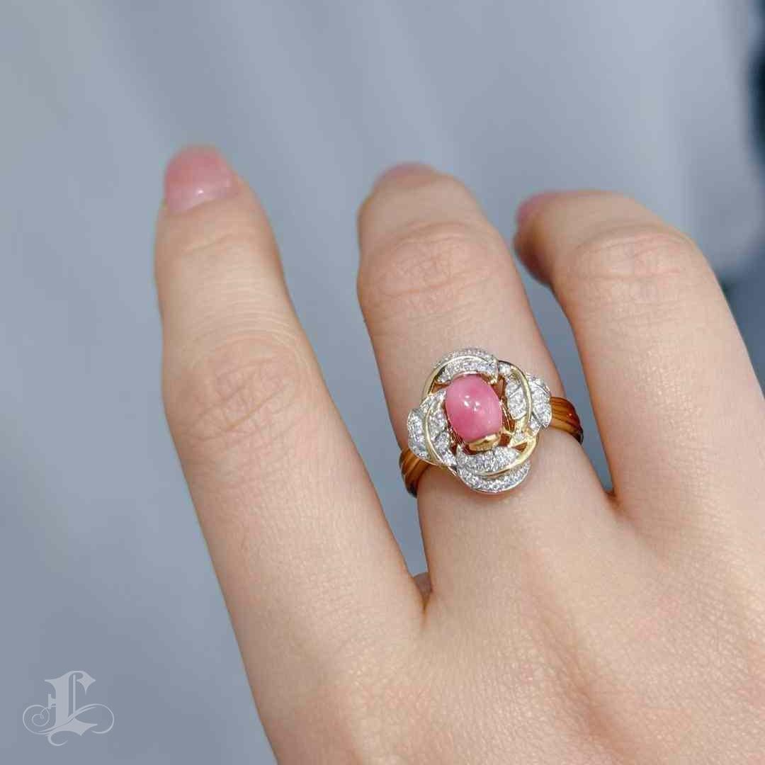 A radiant bloom sculpted in gold and fire, this exceptional ring features a vivid 1.23ct conch pearl in rare Flamingo Pink, glowing with a moderate flame pattern. Cradled within an 18K gold rosette of intertwining diamond-paved leaves, the pearl