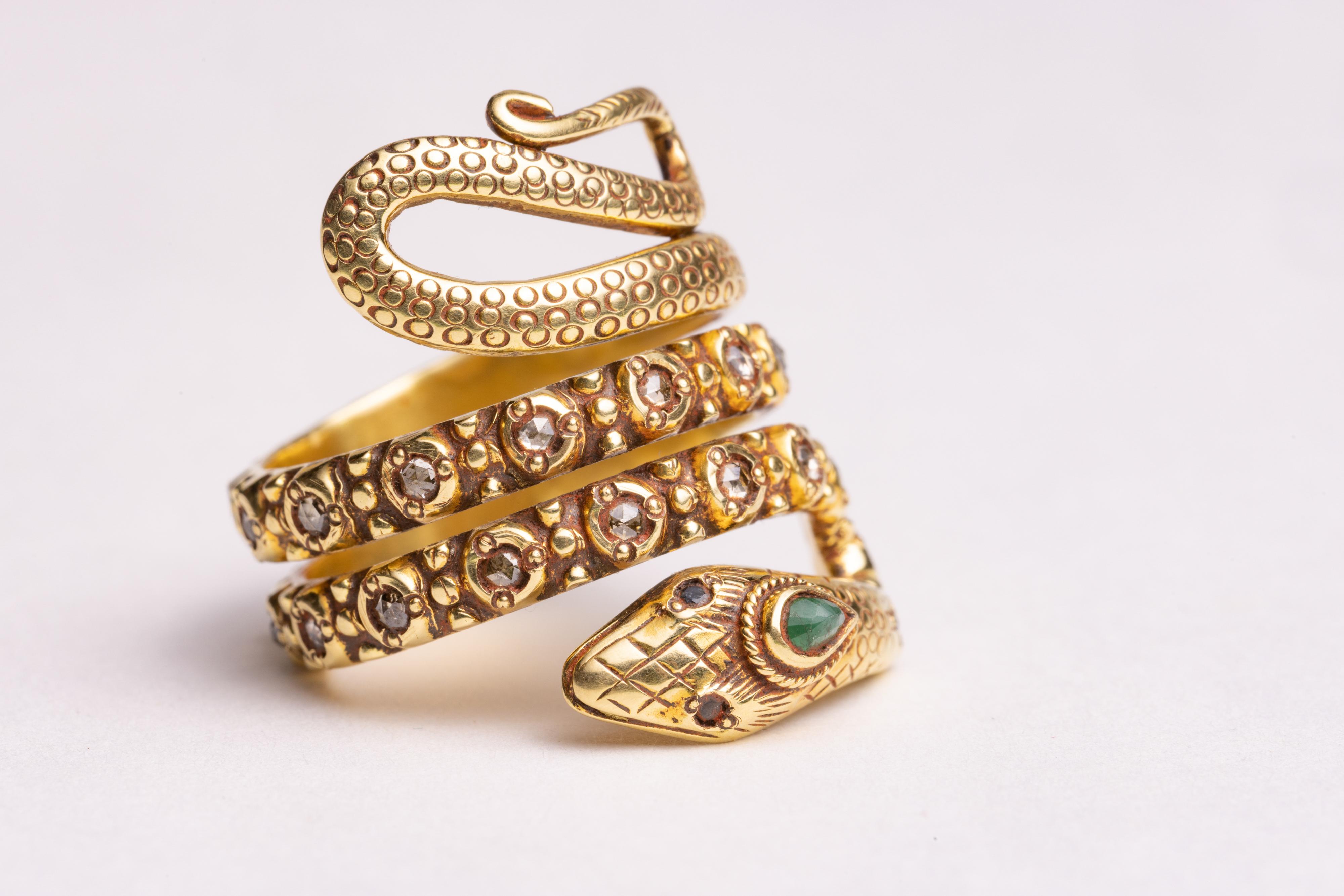 A beautifully hand-crafted coiled snake ring with hand-tooling and granulation work.  Round, faceted diamonds through the middle of the band and a faceted pear-shaped emerald at the third eye and faceted blue sapphire eyes.  Ring size is an 8 with a