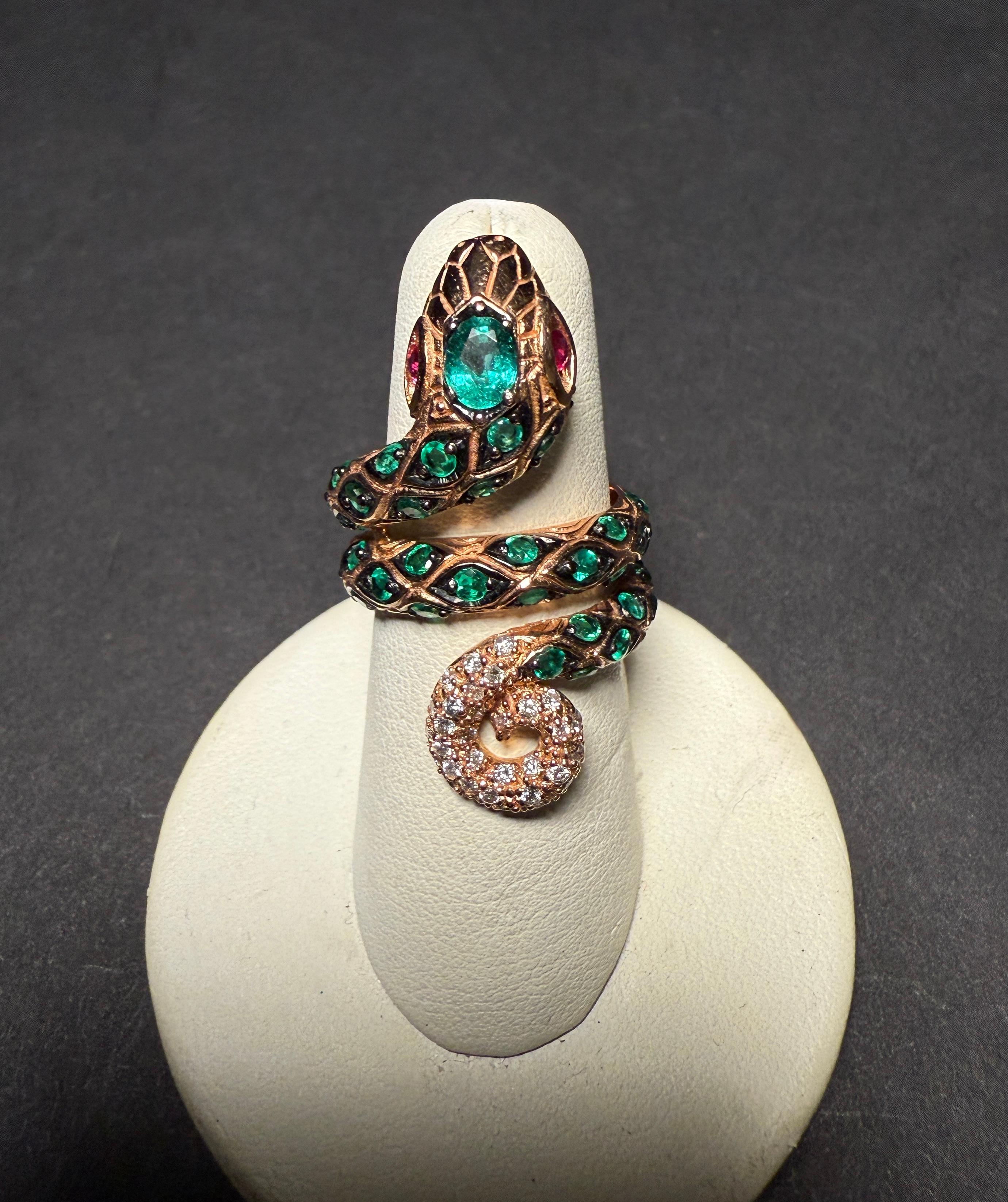 18K yellow gold, emerald and diamond statement ring in the form of a serpent/snake with ruby eyes. Stylishly designed to wrap around your finger and display the elegant form of gold and mixed gems.
38 Round Emeralds, approximately 1.75 cts.
1 Oval