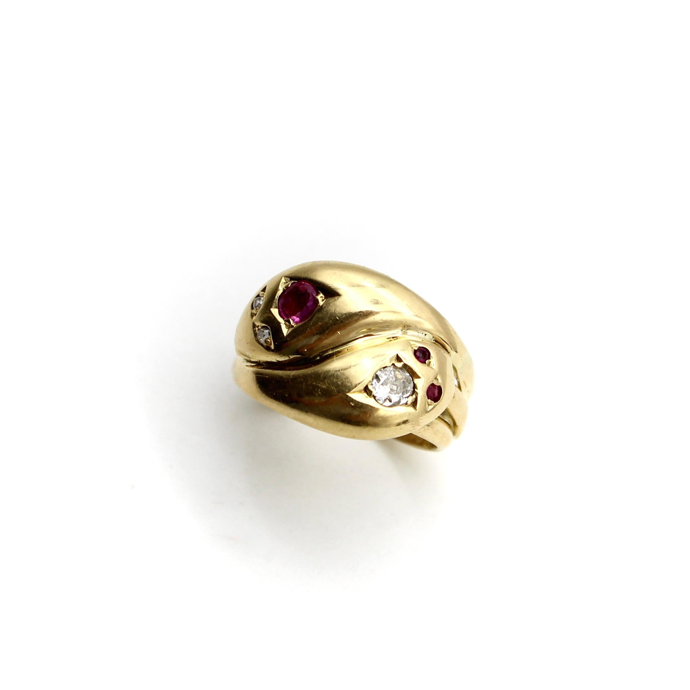 Circa 1917, the heads of two snakes intertwine in this 18k gold Edwardian ring. The snake heads mirror each other: one snake has diamond eyes and a large natural ruby on its back, the other snake has the reverse with ruby eyes and a large Old Mine