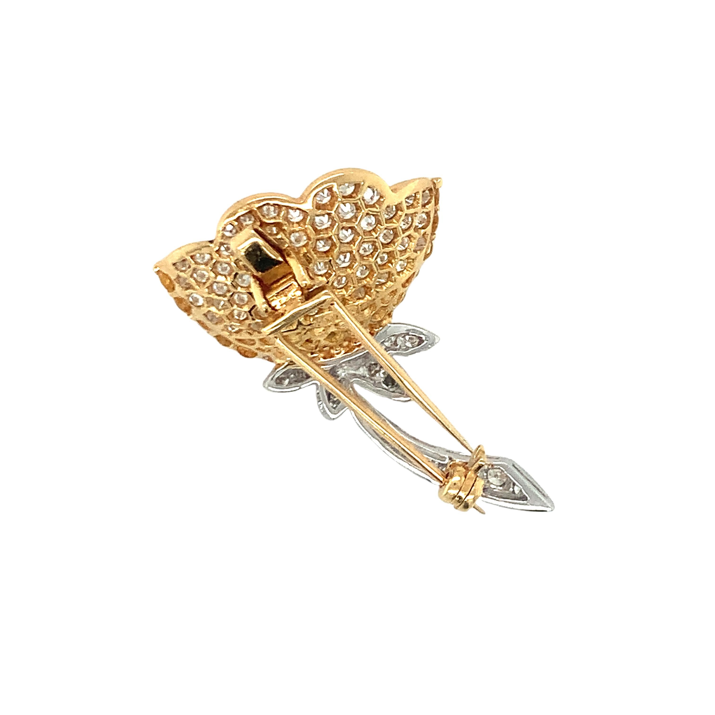 Este exquisito broche de oro amarillo y blanco de 18 quilates es una verdadera obra maestra de elegancia y artesanía, con un deslumbrante diseño floral que irradia sofisticación y encanto contemporáneo. Adornada con 75 diamantes redondos talla