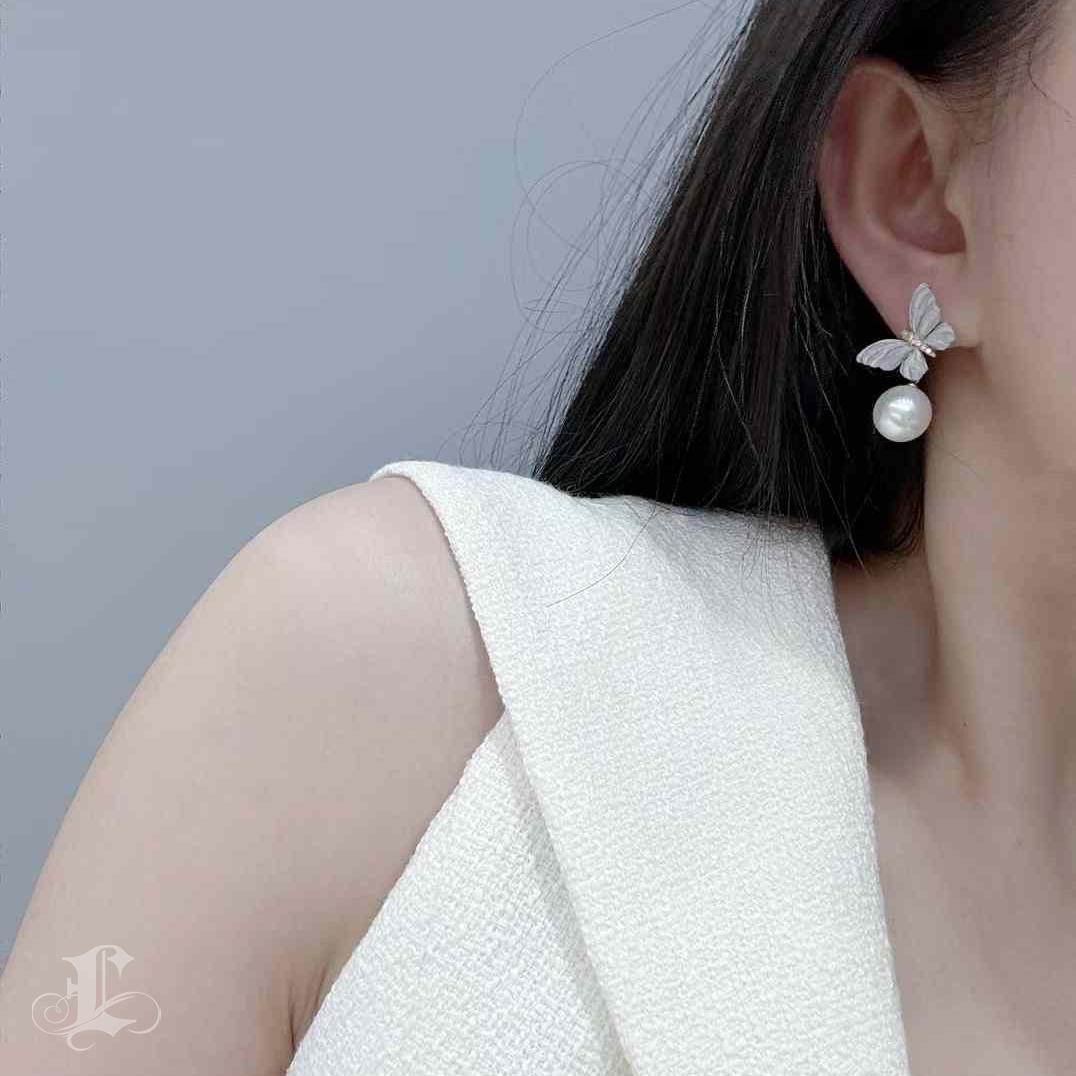 A graceful whisper of spring, this design captures a butterfly mid-flight—its wings gently shimmering with a diamond dust finish, sculpted to mimic the delicate texture of nature. At the heart of each piece glows an Aurora South Sea pearl, softly