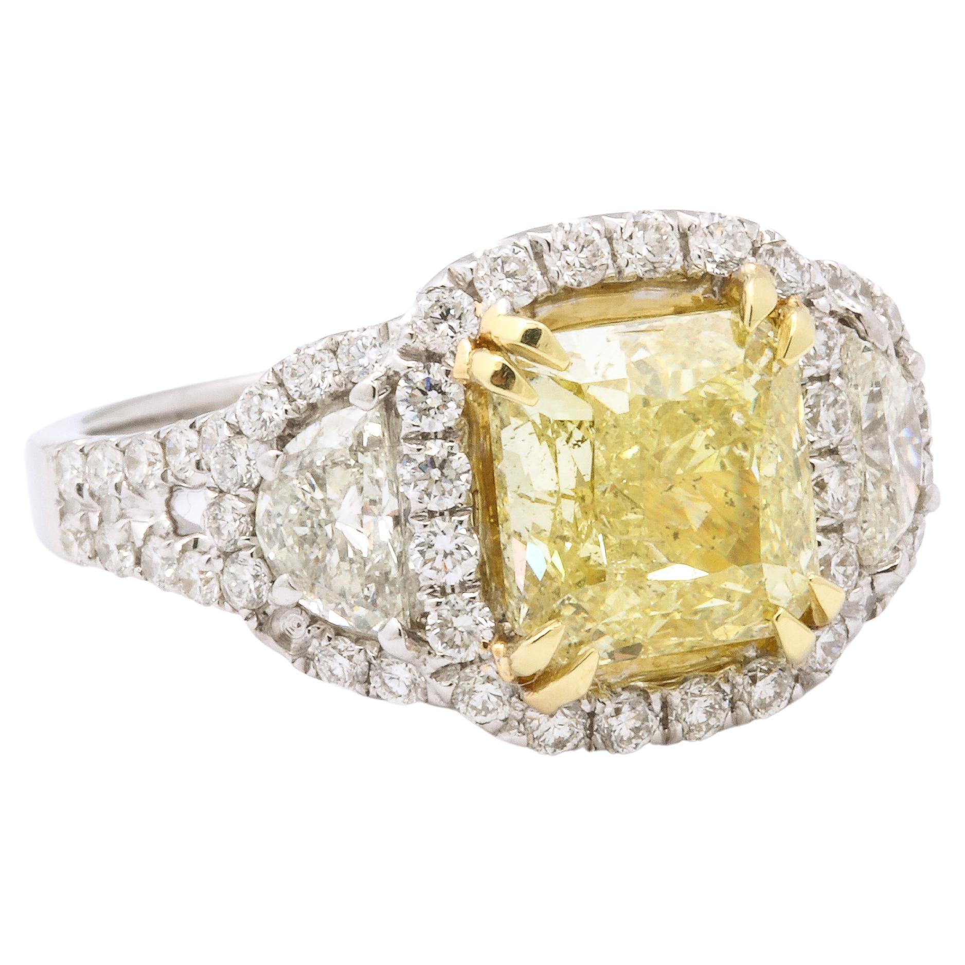 18K Gold Diamond Ring with a center radiant shaped cut yellow diamond. Weighs 3.05 carats, clarity SI-2, color light yellow. Surrounded by two half moon cut diamonds, weighing 0.70 carats, clarity VS-2, color I. Set with round brilliant cut