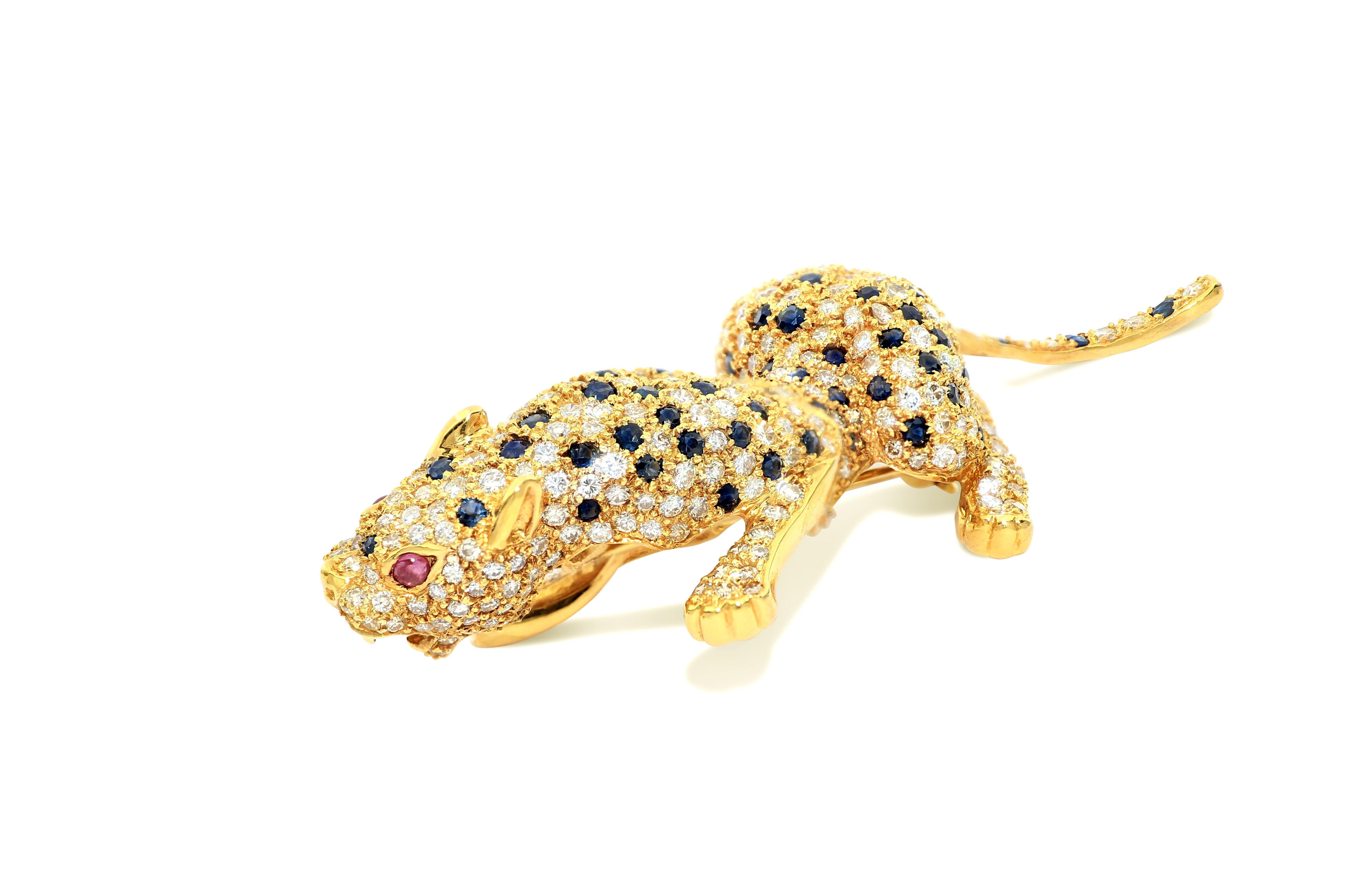 
Dies ist eine prächtige Panther-Diamant-Brosche aus 18 Karat Gelbgold, besetzt mit 354 weißen Diamanten von insgesamt 6,97 Karat, 112 blauen Saphiren von 5,95 Karat und zwei Augen mit zwei Rubinen als Intarsien. Die Panther-Brosche ist lebensecht,