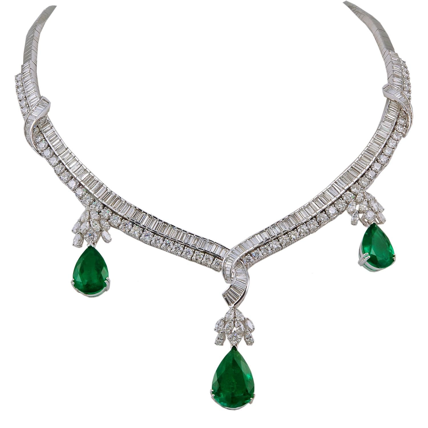 A regal suite comprising a necklace, bracelet, earrings and matching ring, all of similar design, each crafted in 18k white gold set with brilliant diamonds and pear shape emeralds. The suite is comprised with approximately 25 carats of diamonds and