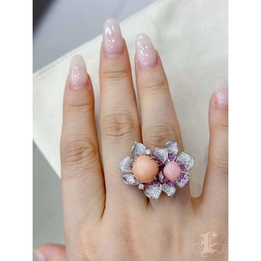 Célébration exquise de la splendeur tranquille de la nature, cette bague florale sculpturale présente non pas une, mais deux perles de conque naturelles rares - une pièce maîtresse rose orangé de 8,6 carats et un accent rose clair de 2,42 carats -