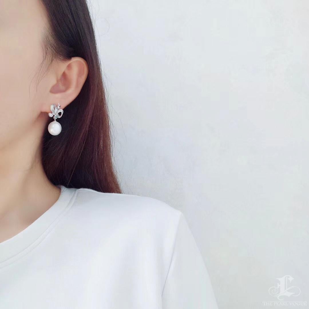 Expressive and refined, these earrings feature sculptural diamond-set ribbons that flutter with movement and light. A brilliant blue topaz anchors the center, leading to a luminous South Sea pearl in a soft oval silhouette.
Designed in 18K white