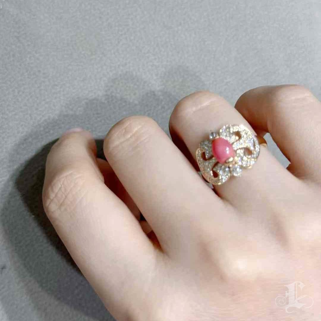 A graceful homage to vintage glamour, this artistic ring showcases the enchanting beauty of a 1.65ct flamingo pink conch pearl. With a symmetrical drop shape and a moderate flame pattern, the pearl glows from within, exuding timeless femininity. The