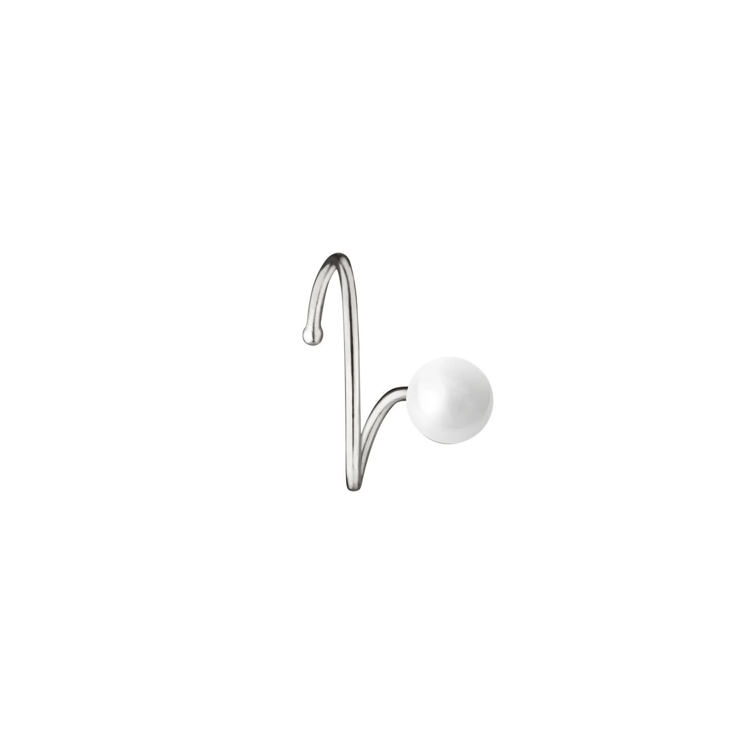 N 7 es un refinado ear cuff diseñado como una tranquila exploración del equilibrio, la ligereza y la forma. En su centro descansa una perla luminosa que brilla suavemente, delicadamente suspendida dentro de un marco escultural. La pieza parece