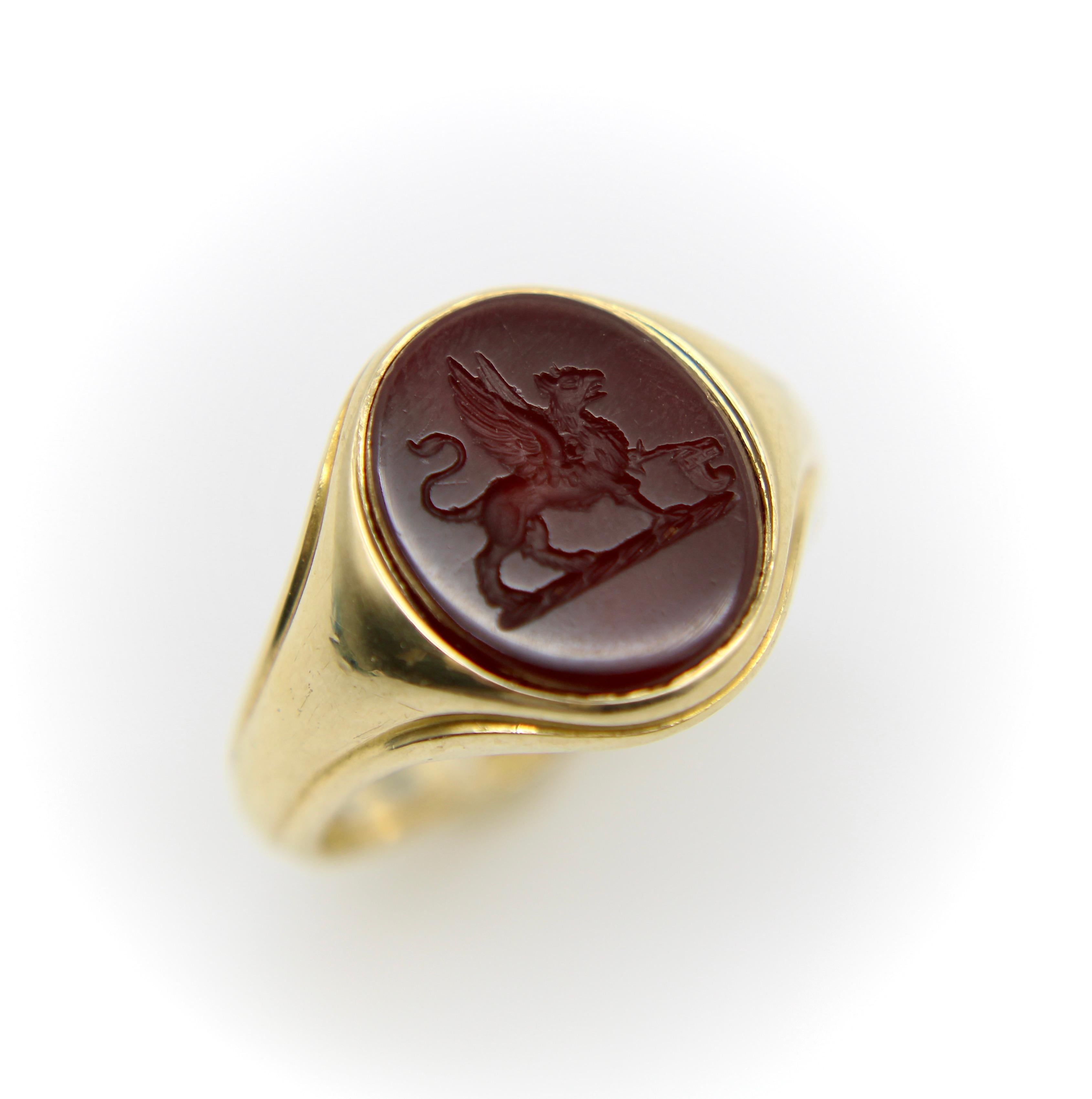 This 18k gold early Victorian intaglio ring features a griffin beautifully carved into a dark reddish brown agate. In this classic rendition of the griffin, the winged beast has a curved tail and rests its paws on the remnants of a corinthian