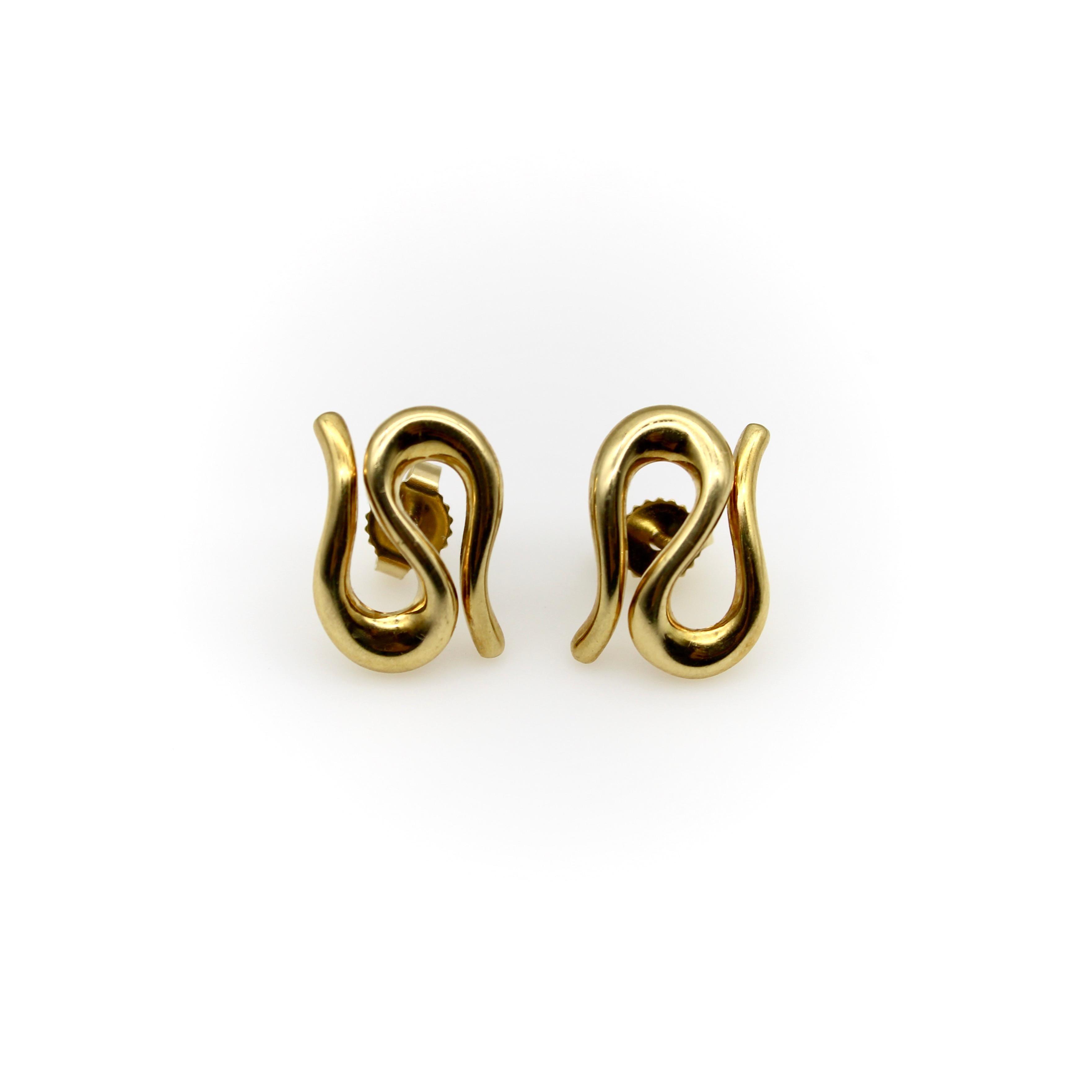 These stunning 18k gold earrings are a rare Tiffany & Co. Elsa Peretti design, circa the 1980’s. Their sinuous form folds back on itself in an elegant curve—the body of a snake without a head or tail. Like many of Elsa Peretti’s designs, they are a