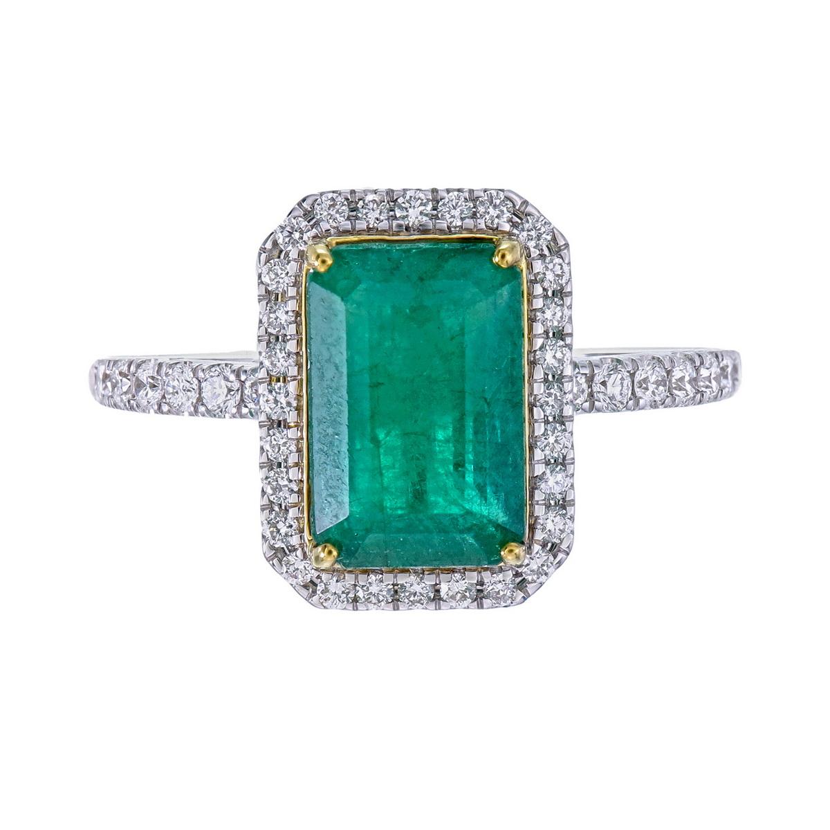 Dieser meisterhaft aus 18-karätigem Gold gefertigte Ring ist ein auffallendes Statement der Eleganz und präsentiert in seiner Mitte einen leuchtenden Smaragd im Smaragdschliff. Der sattgrüne Edelstein wird von einem Kranz funkelnder runder Diamanten