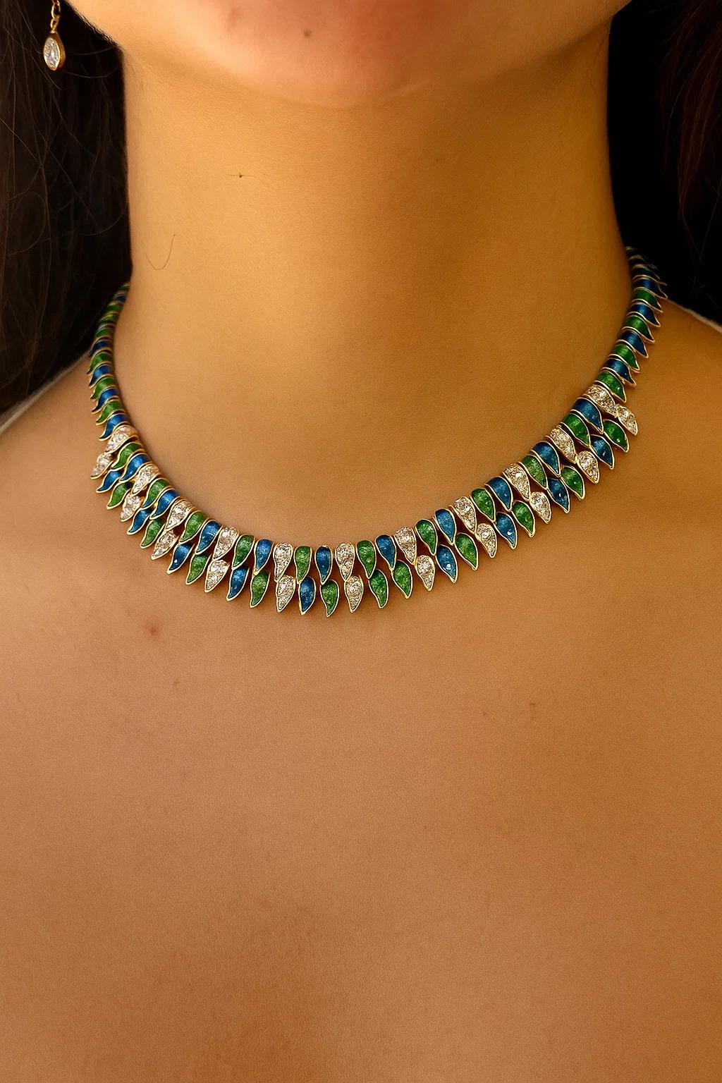 This estate collar necklace is a rare and striking piece, crafted in luxurious 18K yellow gold and designed with alternating sections of vivid blue and rich green enamel. The enamel work, done in a sleek marquise shape, creates a rhythmic, elegant