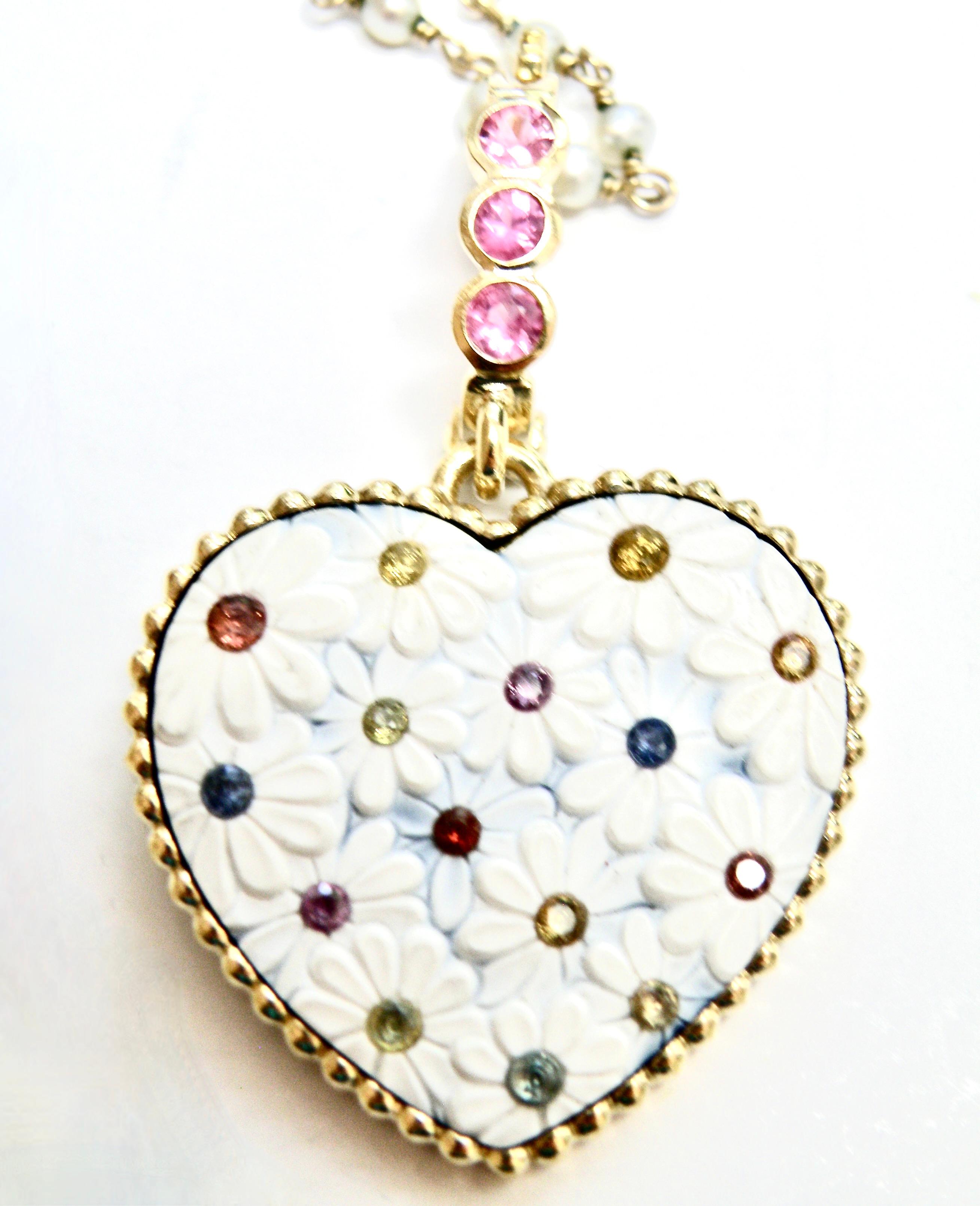 Scolpito dal famoso scalpellino tedesco Idar Oberstein. Il cuore di Howlite è intagliato con margherite e poi, al centro, è incastonato con zaffiri multicolori.  L'Enhancer rimovibile da 18 carati è incastonato con zaffiri rosa. 