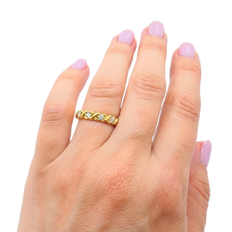 18k gold eternity ring featuring a twisted design and set with diamonds.  Eternity rings are designed to symbolize never-ending love, often given for anniversaries or significant milestones.  The twisted element adds a unique textural dimension to