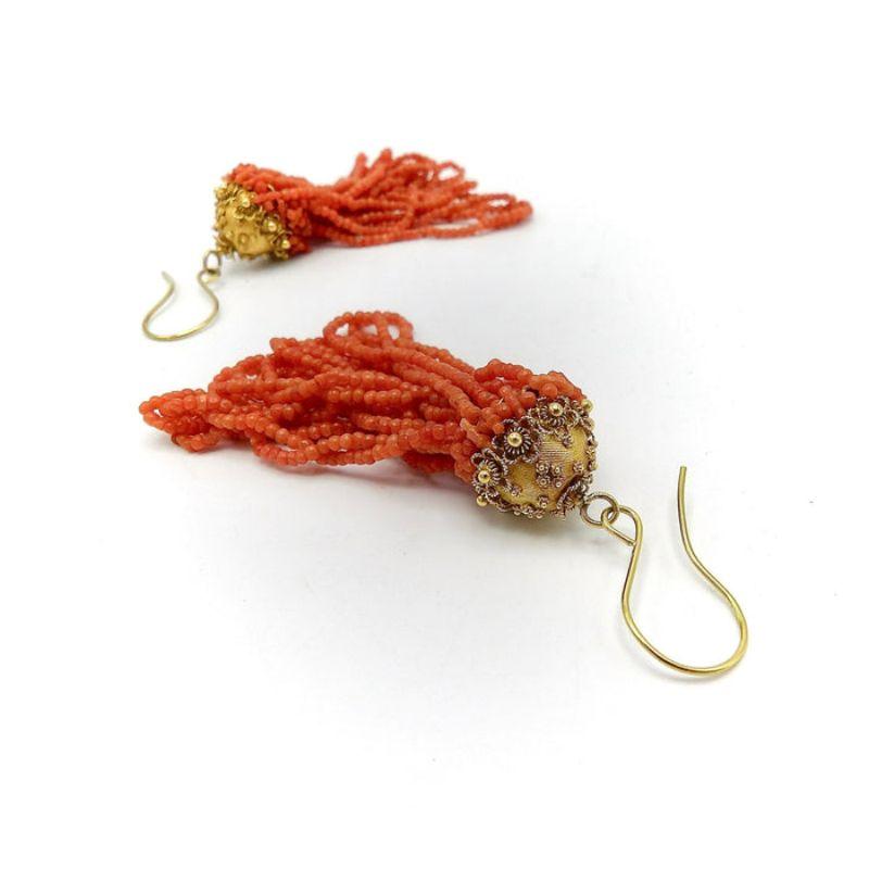 These very special earrings are Etruscan Revival, made of 18 karat gold with dangling beaded coral gemstones. Inspired by the Etruscans, jewelers implemented the use of wirework, beading, filigree and granulation. The gold wirework on these earrings