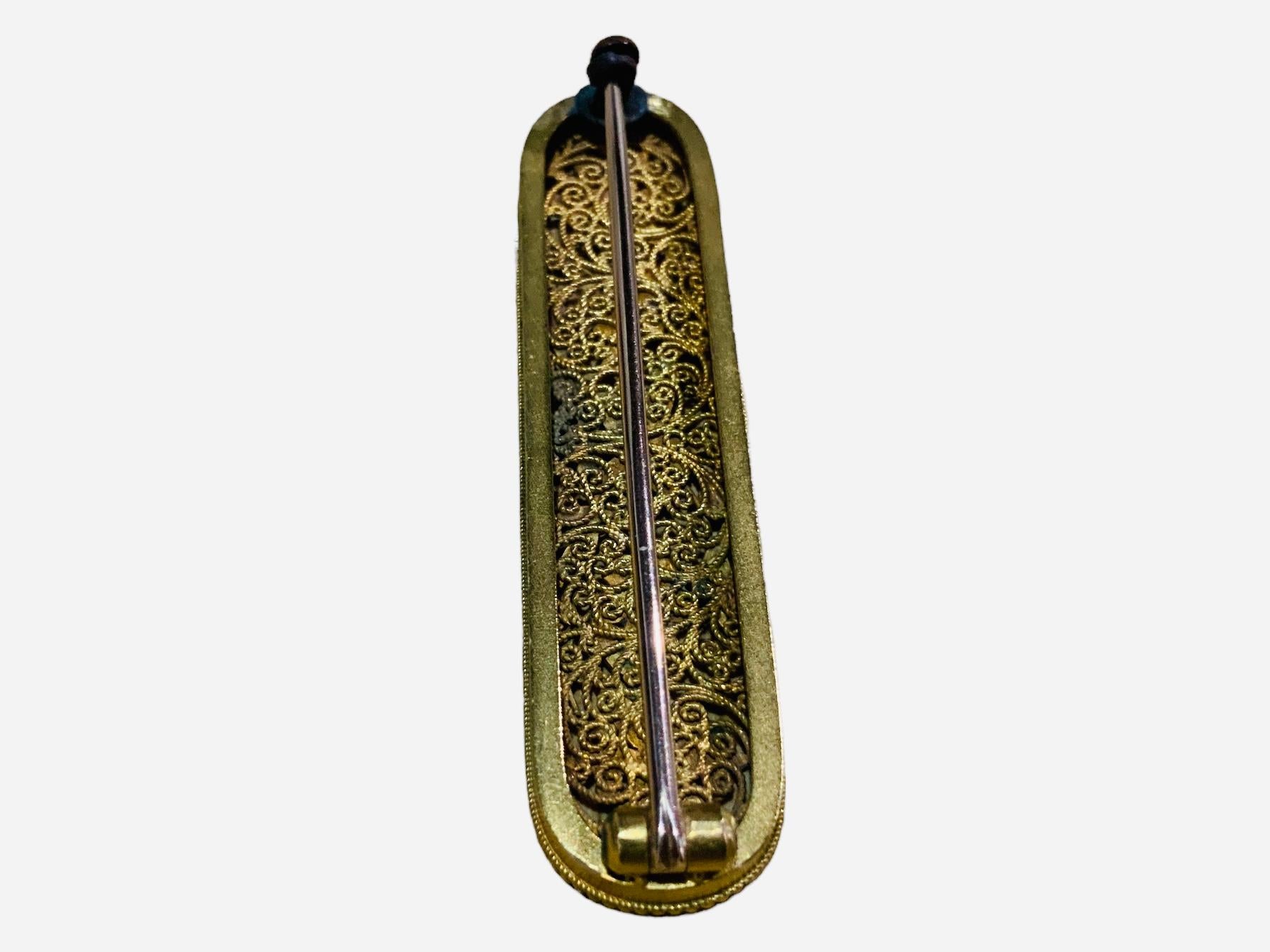 This is an 18K yellow gold enamel floral elongated oval brooch. The brooch is adorned with a colorful mixed of flowers with foliages in the center. Its border is decorated with gold beads. In the back, the brooch closes with a C-clasp.