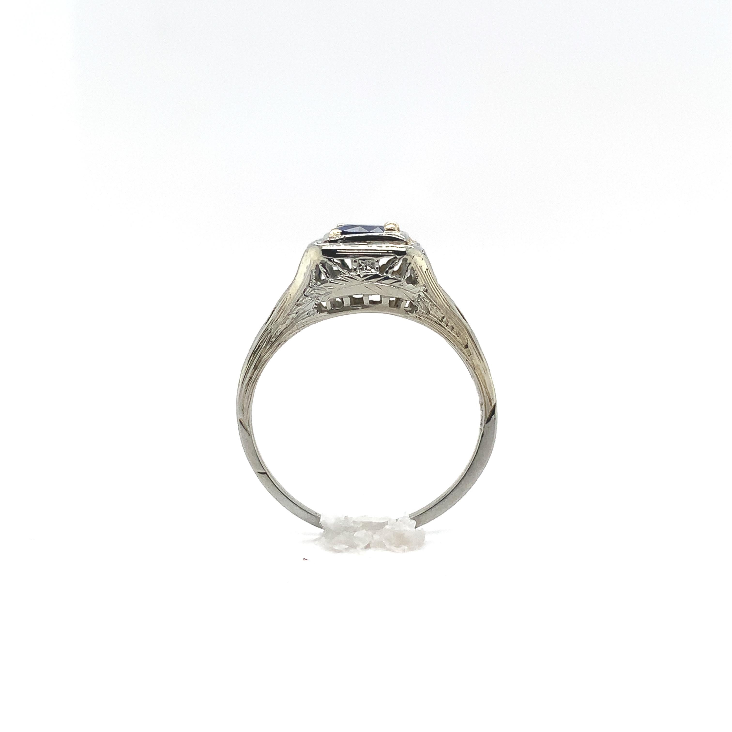 Filigraner Ring aus 18 Karat Weißgold im Art-Deco-Stil mit einem runden, echten blauen Saphir von 0,57 Karat. Der Saphir hat eine dunkelblaue Farbe und misst etwa 4,8 mm.  Es gibt handgravierte Details und auch einen glatten Bereich, in dem Ringe
